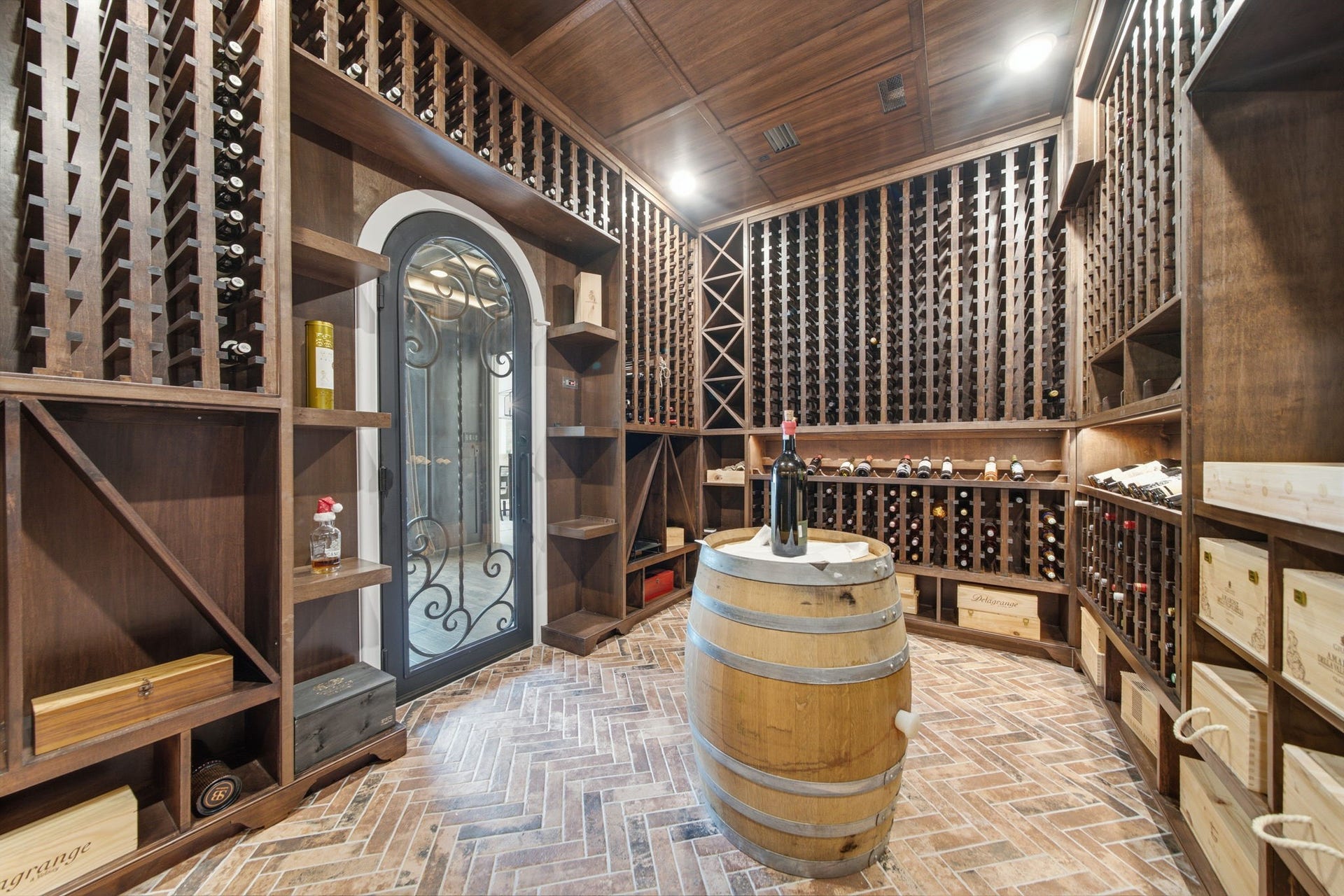 6310 Star Light Court, Spring, TX 77386 Luxurious wine cellar with custom wooden racks, elegant brick flooring, and a stylish barrel table centerpiece, perfect for wine enthusiasts.