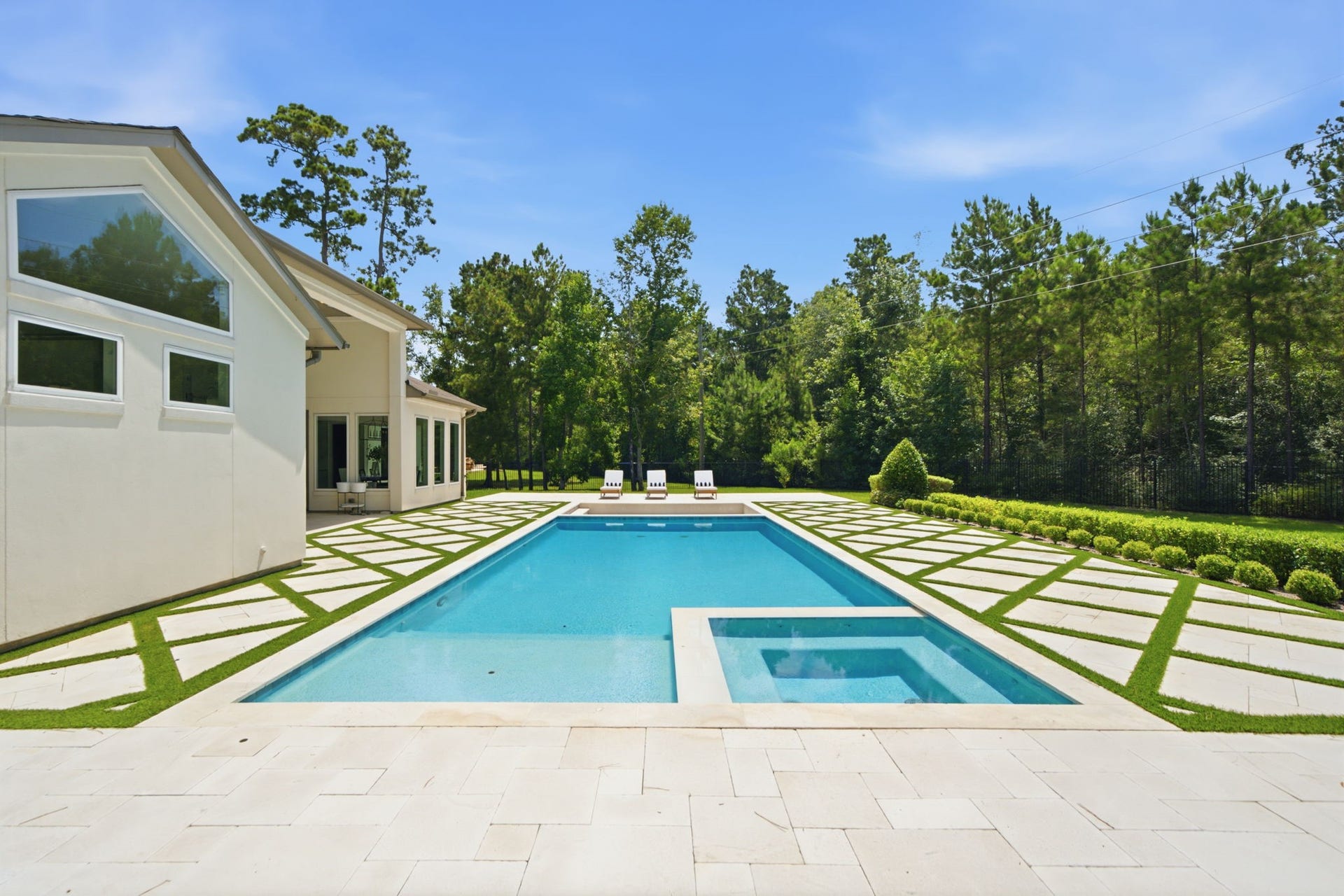 6310 Star Light Court, Spring, TX 77386 Luxurious modern home featuring a stunning outdoor pool and spa, surrounded by a beautifully landscaped yard with lush greenery and ample space for relaxation.