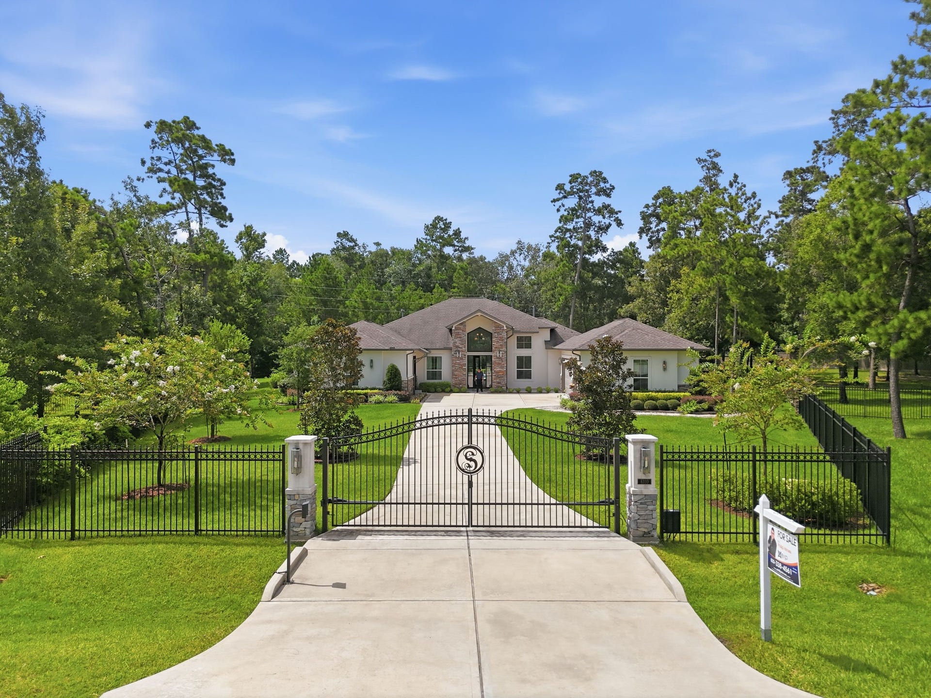6310 Star Light Court, Spring, TX 77386 Luxurious estate with a grand gated entrance, surrounded by lush greenery and a beautifully manicured lawn, offering privacy and elegance.