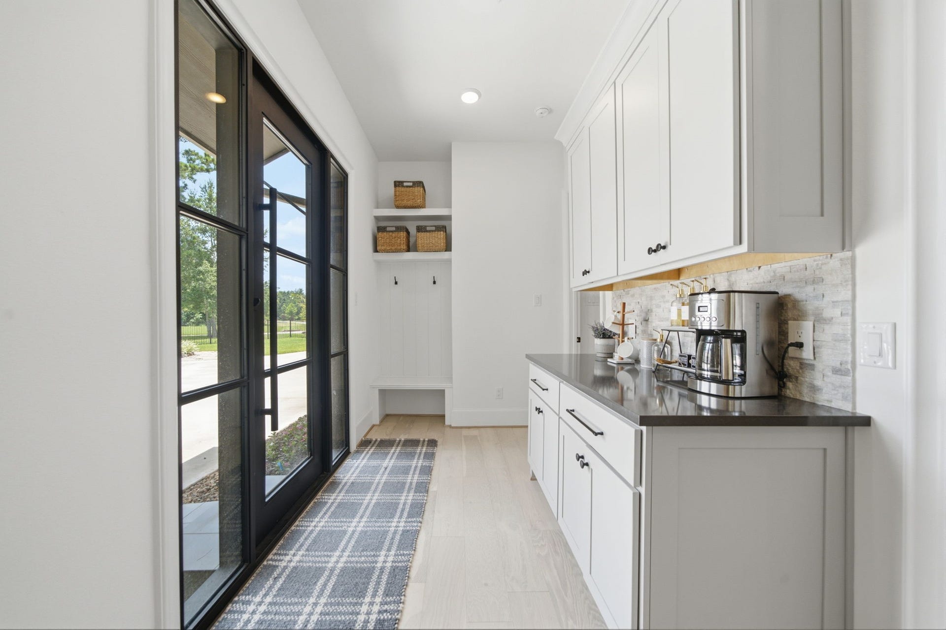 6310 Star Light Court, Spring, TX 77386 Bright and inviting mudroom with sleek cabinetry, ample storage, and large glass doors offering a view of the outdoors.
