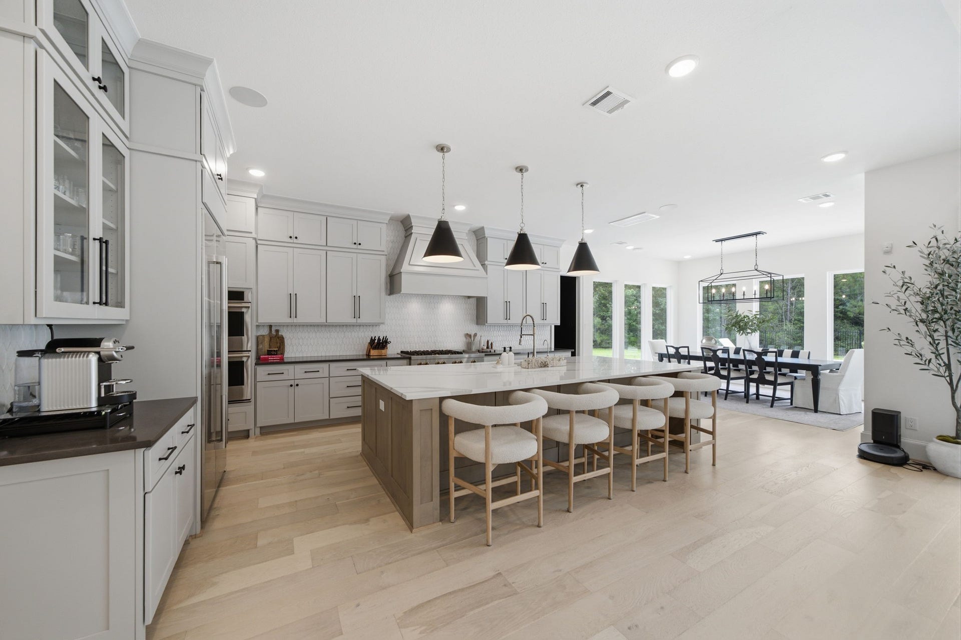 6310 Star Light Court, Spring, TX 77386 Spacious and elegant kitchen with modern cabinetry, a large island with seating, and stylish pendant lighting, seamlessly flowing into a bright dining area with large windows.