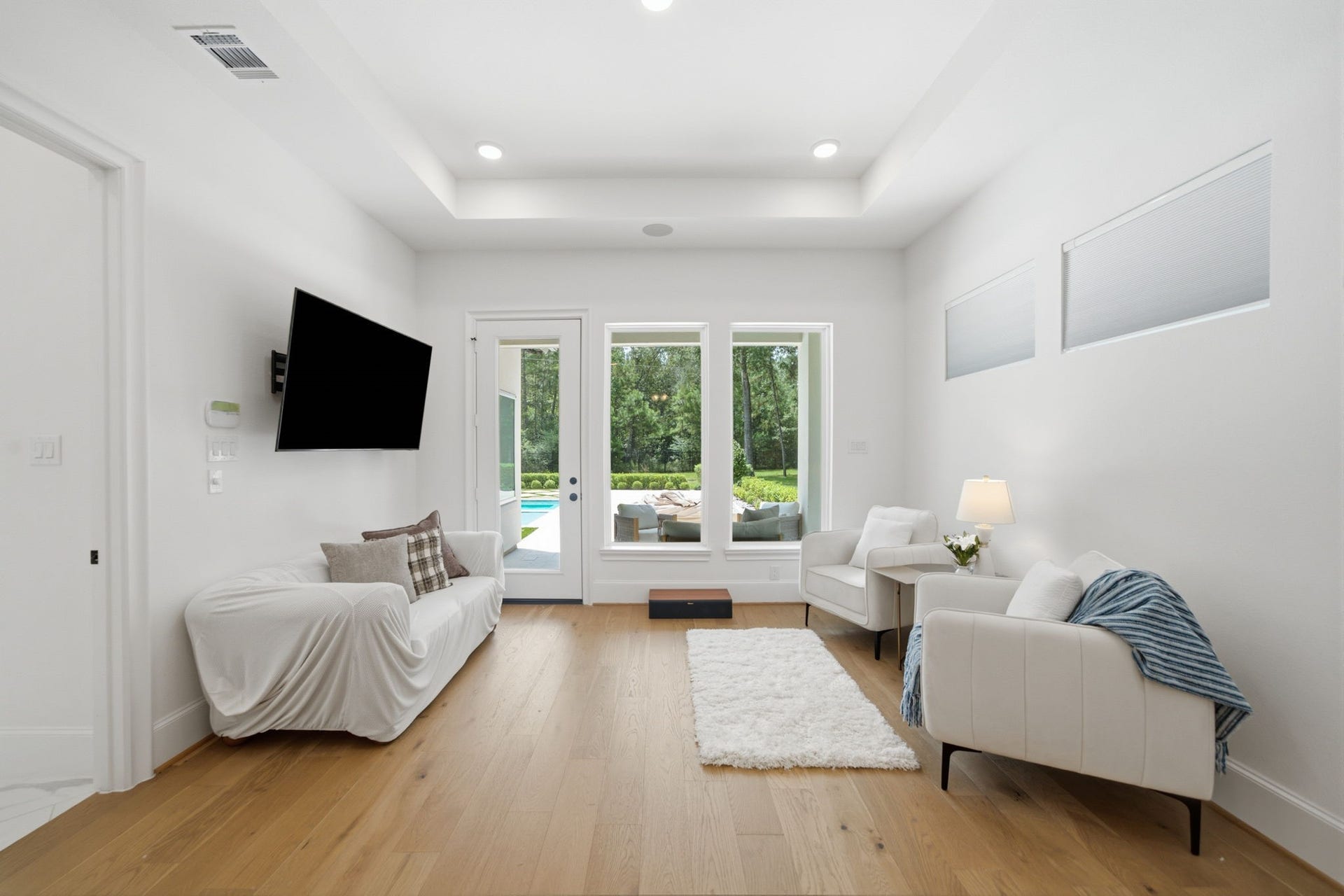 6310 Star Light Court, Spring, TX 77386 Bright and inviting living area with sleek hardwood floors, modern furnishings, and large windows offering scenic views of the backyard and pool.