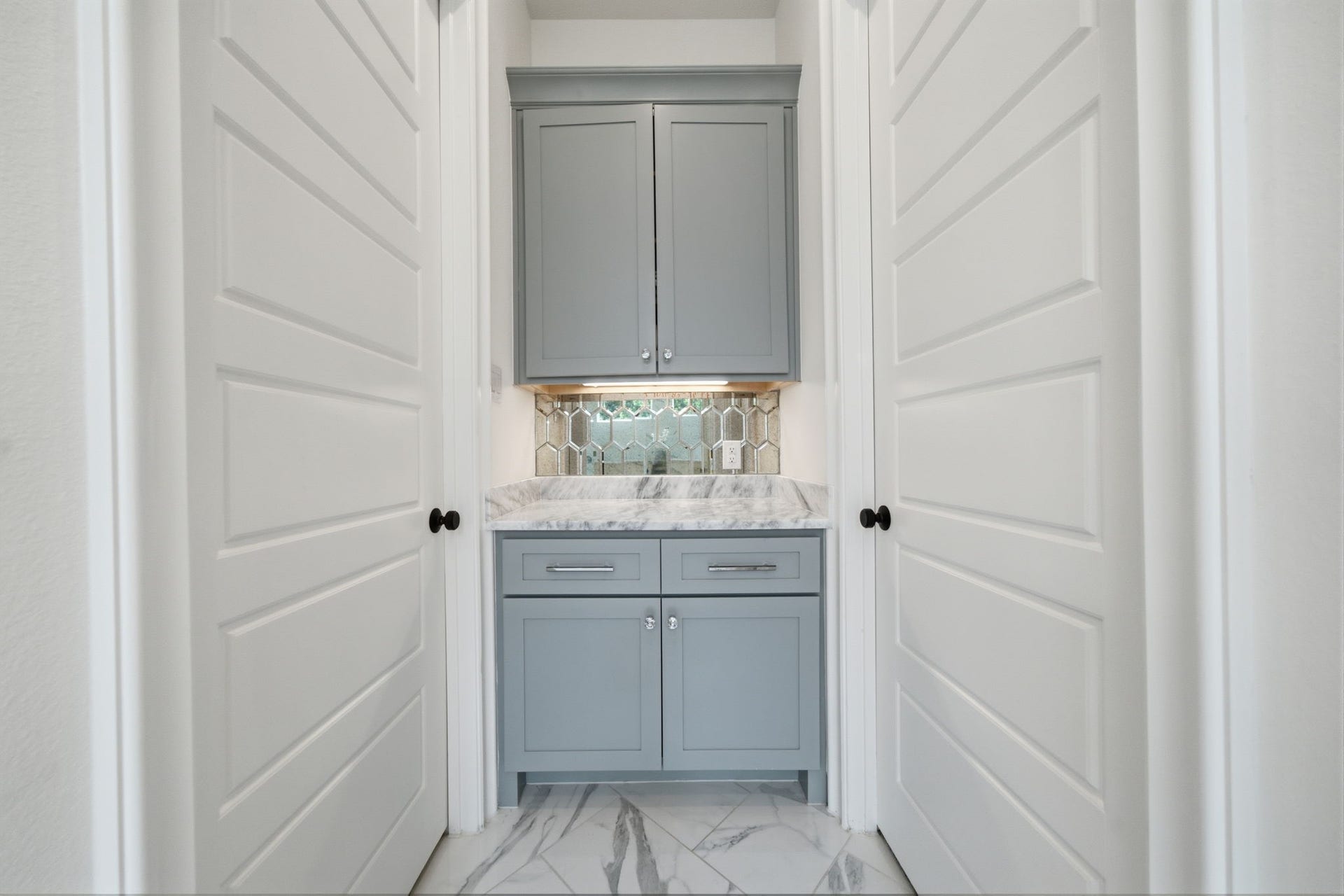 6310 Star Light Court, Spring, TX 77386 Elegant hallway nook featuring sleek gray cabinetry with marble countertops and a stylish hexagonal tile backsplash.
