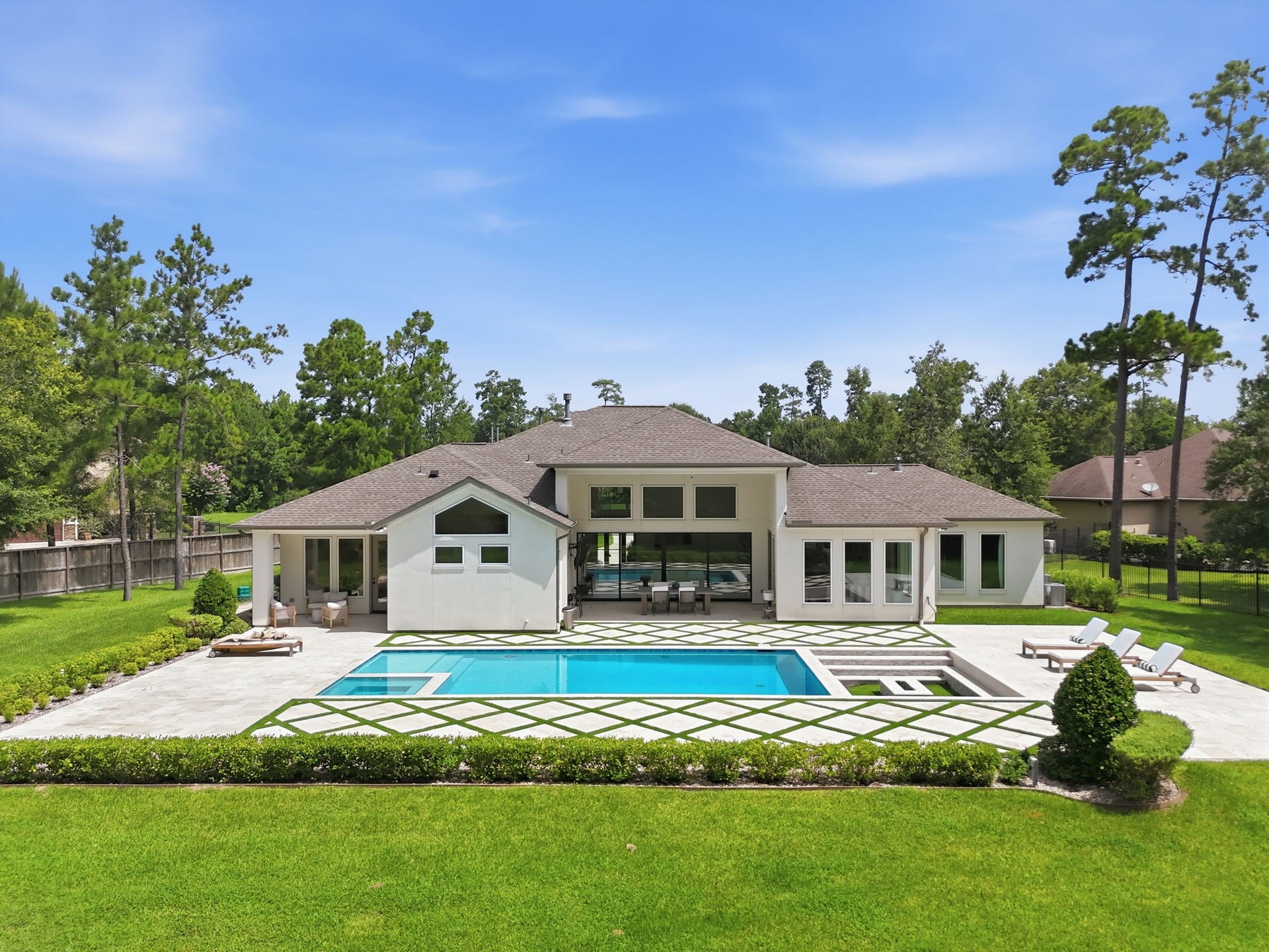 6310 Star Light Court, Spring, TX 77386 Luxurious modern home with expansive backyard featuring a pristine pool, surrounded by lush greenery and spacious patio areas, perfect for entertaining and relaxation.