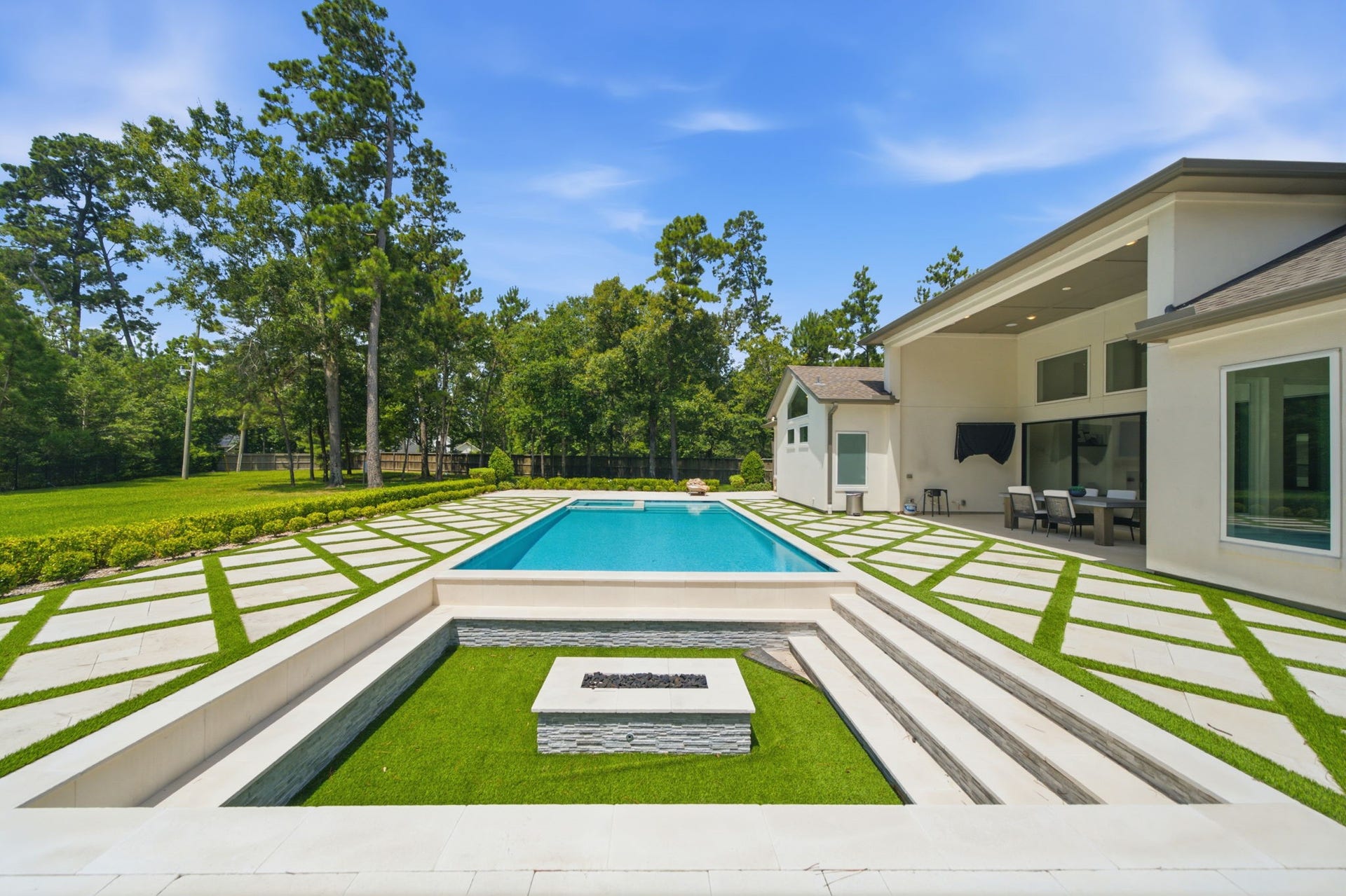 6310 Star Light Court, Spring, TX 77386 Luxurious backyard oasis featuring a sleek swimming pool, modern patio with a covered dining area, and elegant landscaping surrounded by lush greenery.