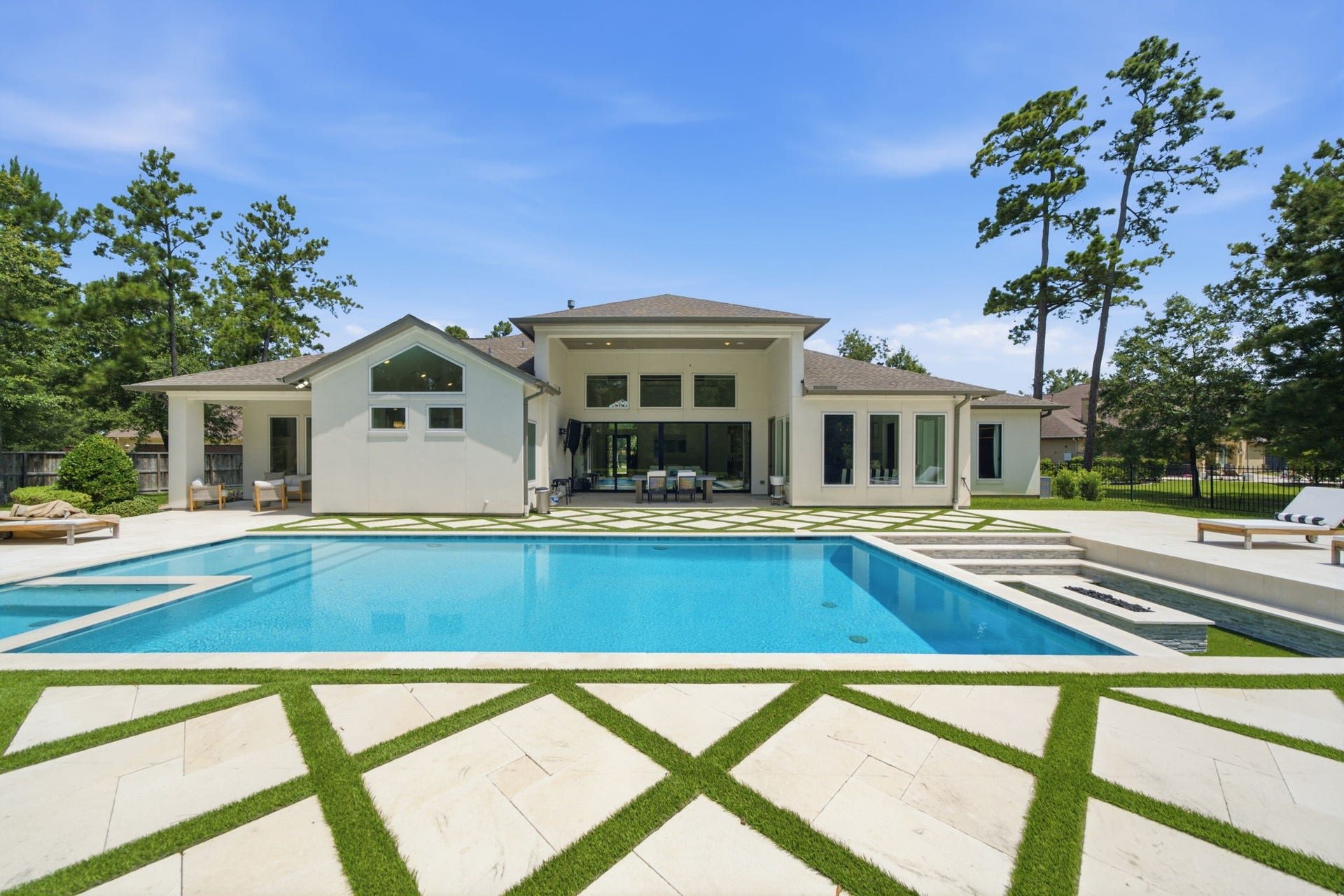 6310 Star Light Court, Spring, TX 77386 Luxurious modern home featuring an expansive backyard with a pristine swimming pool, surrounded by elegant landscaping and ample lounging areas for relaxation and entertainment.