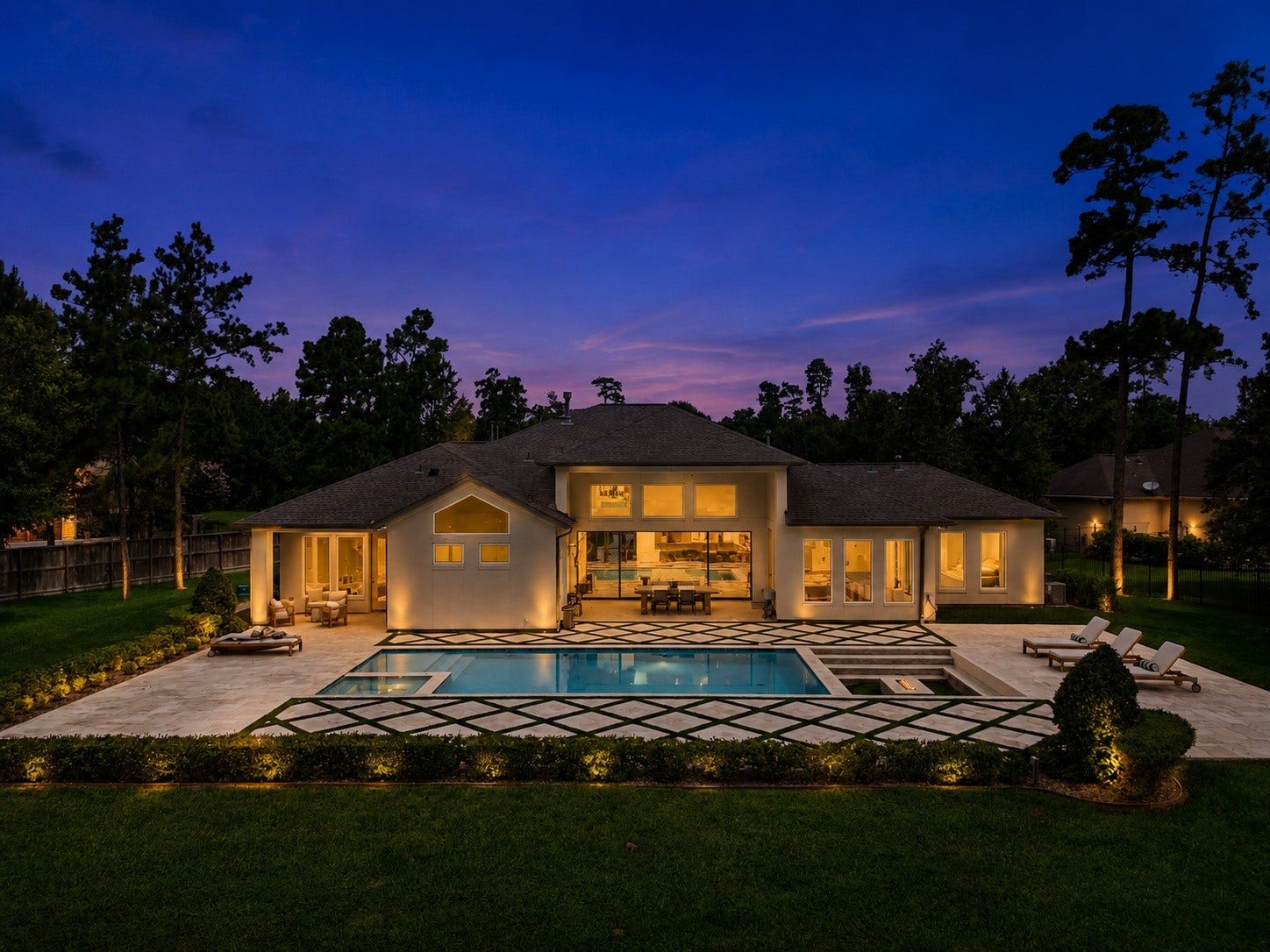 6310 Star Light Court, Spring, TX 77386 Experience luxury living in this stunning home featuring a beautifully lit backyard with a modern pool, spacious patio, gas fire pit, and elegant landscaping, all set against a picturesque evening sky.