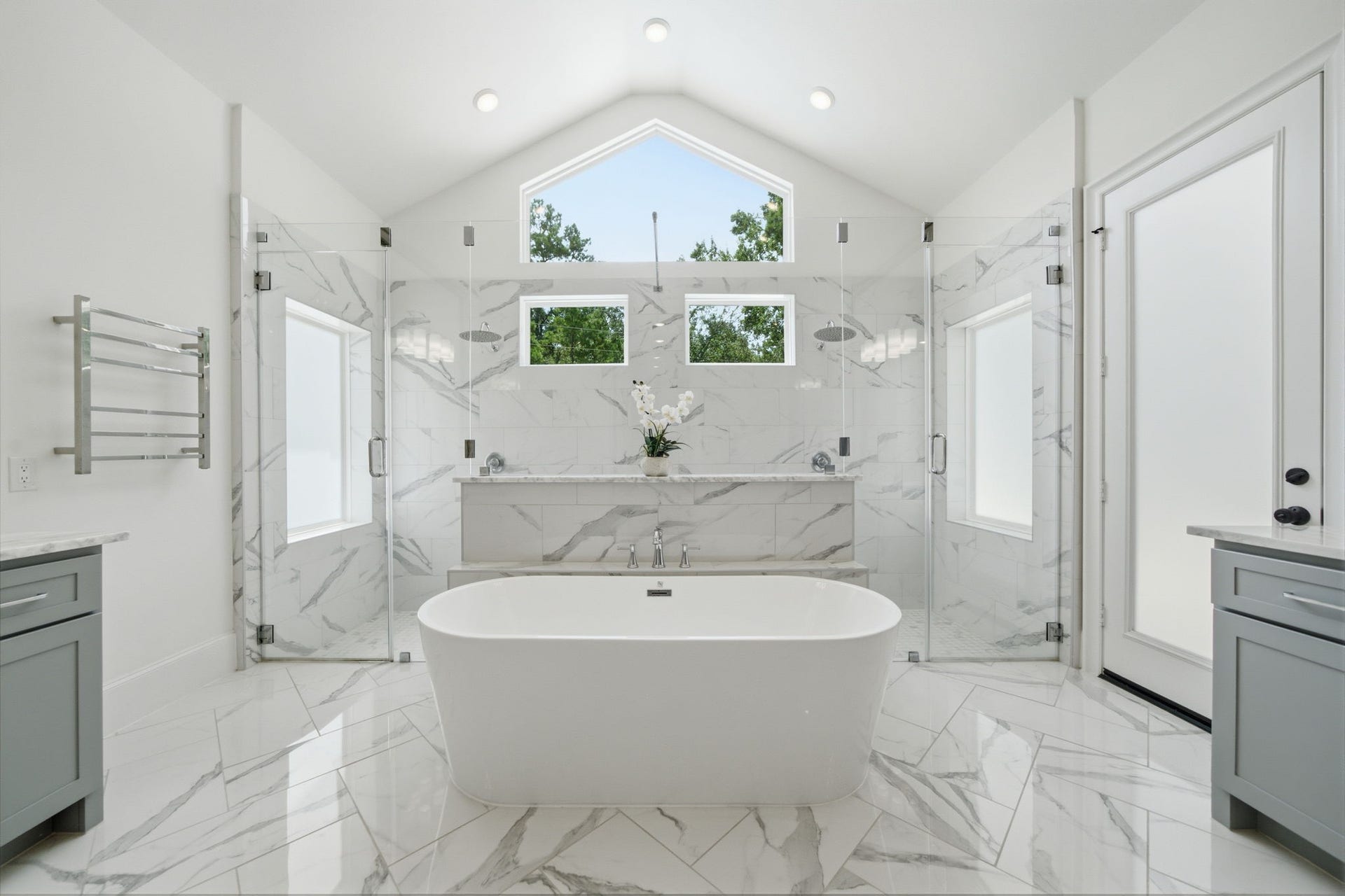 6310 Star Light Court, Spring, TX 77386 Luxurious bathroom featuring a freestanding tub, dual glass-enclosed showers, and elegant marble finishes, all under a vaulted ceiling with abundant natural light.