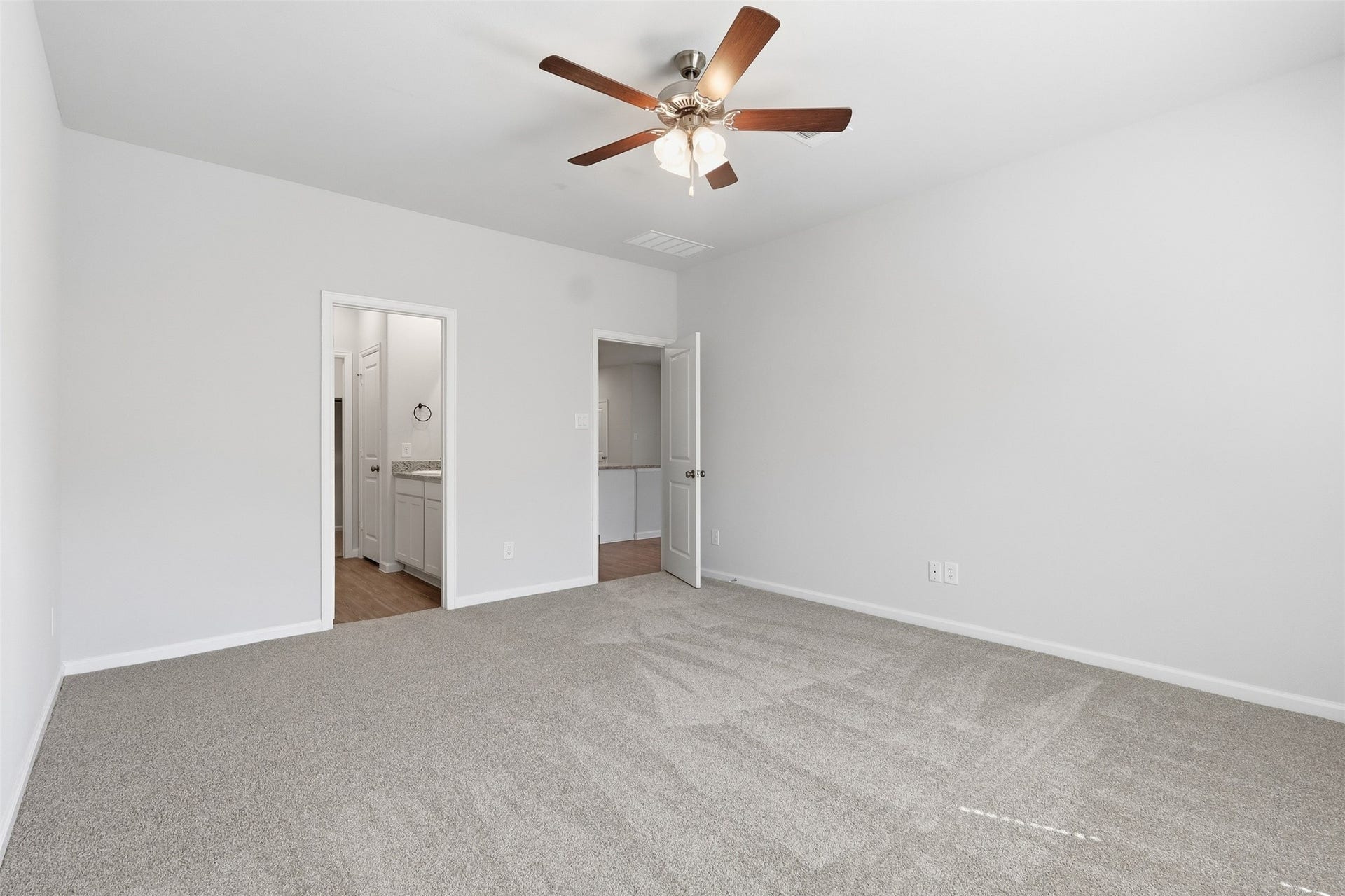 29 Valiant Ridge Trail, Magnolia, TX 77354 Spacious primary bedroom with new plush carpeting, large windows for natural light, and a ceiling fan for comfort