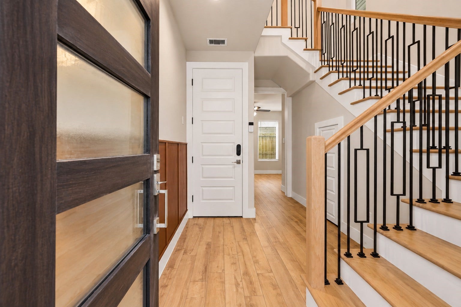 3109 Arlington Street, Houston, TX 77018 Inviting entryway featuring luxury vinyl plank flooring, neutral finishes, and a striking modern staircase with wood treads and geometric black iron railings.