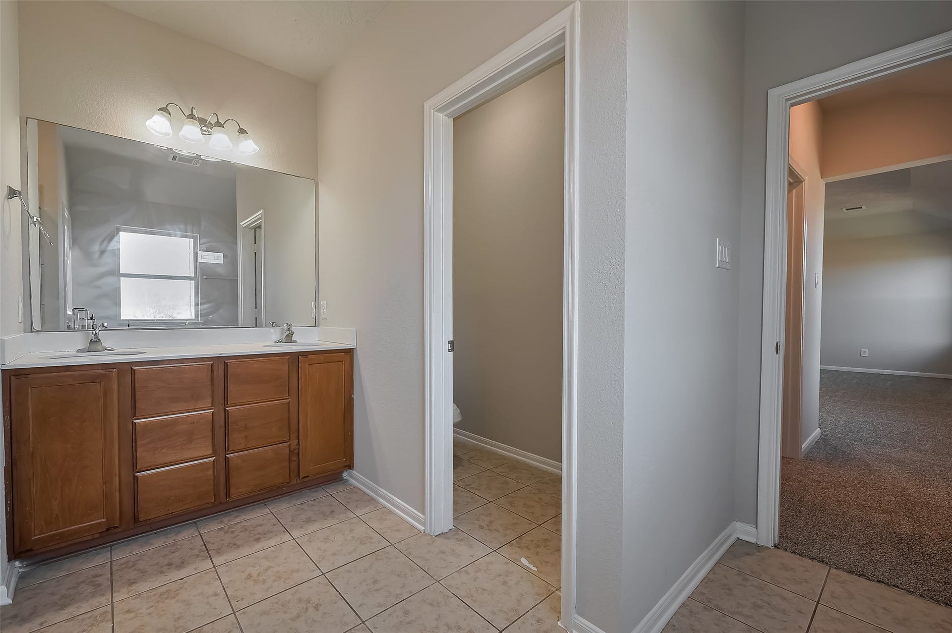 24114 Morrison Lane, Katy, TX 77493 Primary Bathroom with dual sinks, a large mirror & wooden cabinetry.