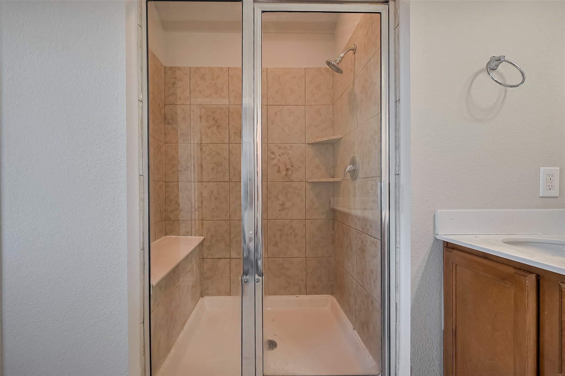24114 Morrison Lane, Katy, TX 77493 Shower with a glass door, built-in shelving, and a bench.
