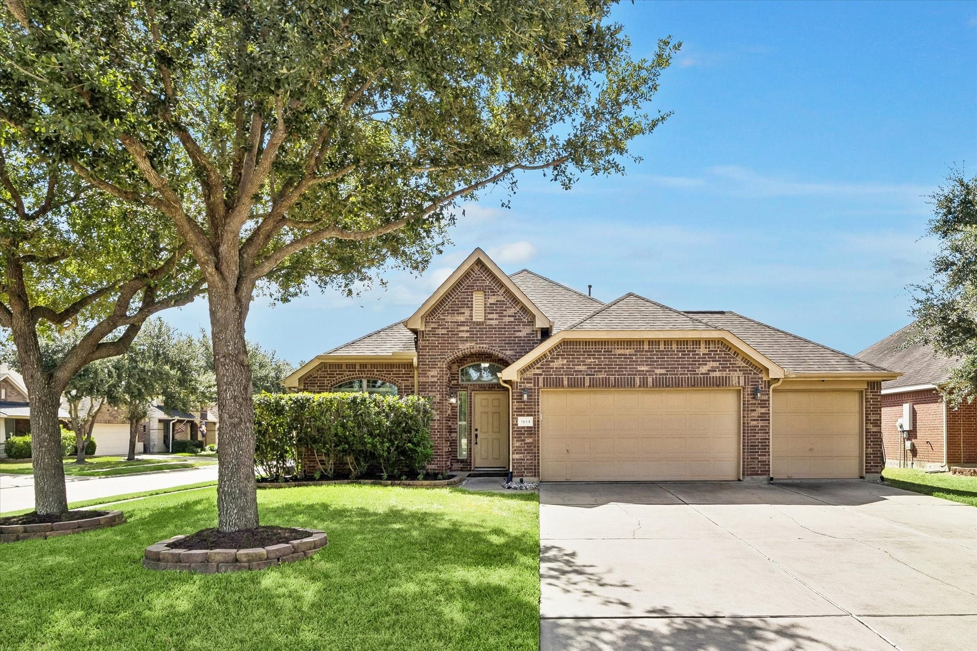 Front Exterior  Hero Photo - Welcome to 1614 Colonial Crest Drive. Mature trees frame the brick exterior, while the broad driveway and multi-bay garage configuration immediately showcase the home's curb appeal and functionality.