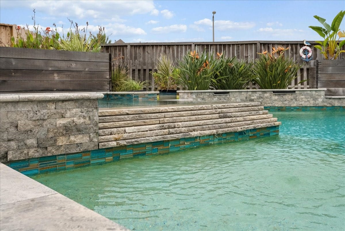 Your backyard paradise features a resort-style pool, spa, cedar pergola, covered patio, expansive travertine decking, and outdoor kitchen designed for entertaining!