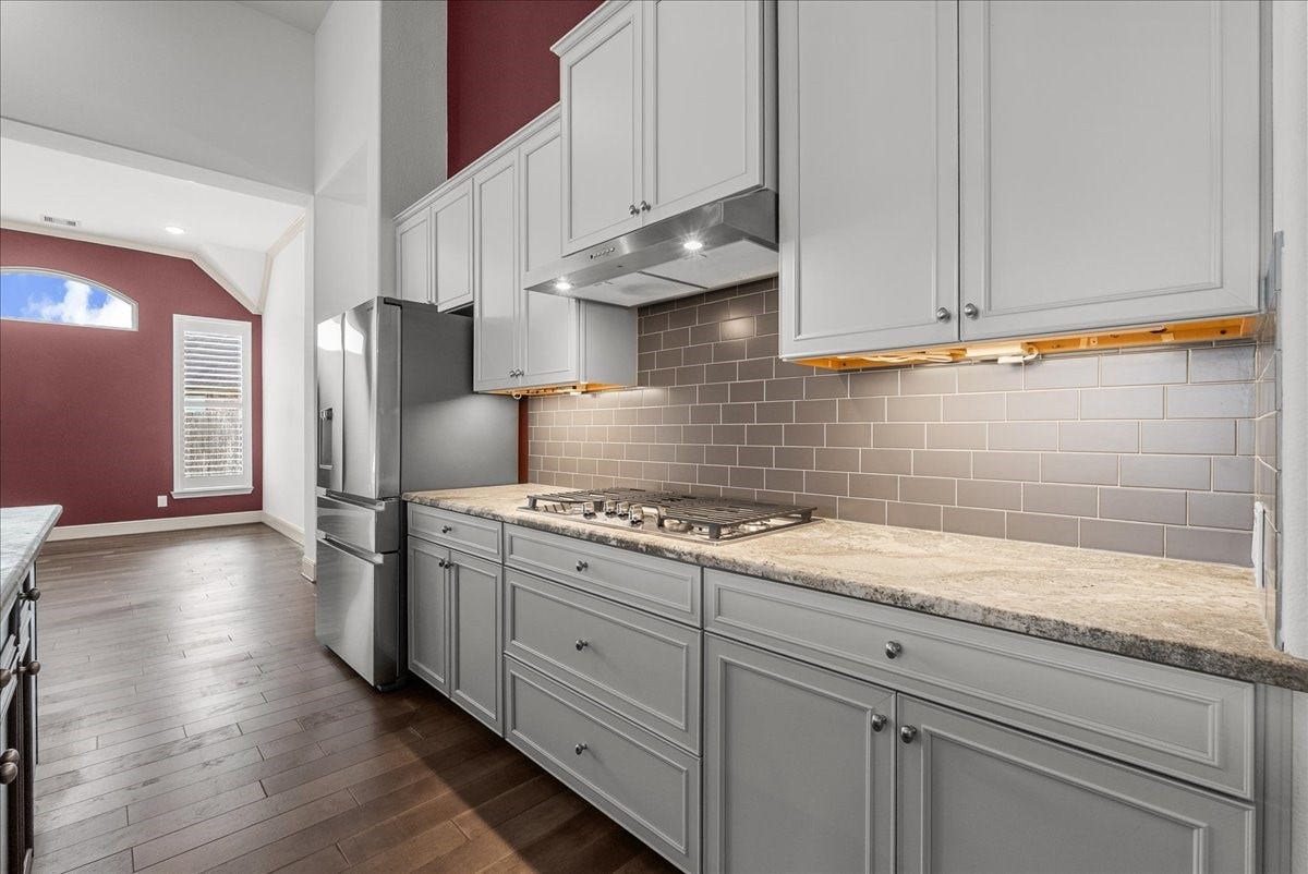 The gourmet kitchen impresses with an oversized granite island, stainless steel appliances, under cabinet lighting, walk-in pantry, and abundant cabinetry.