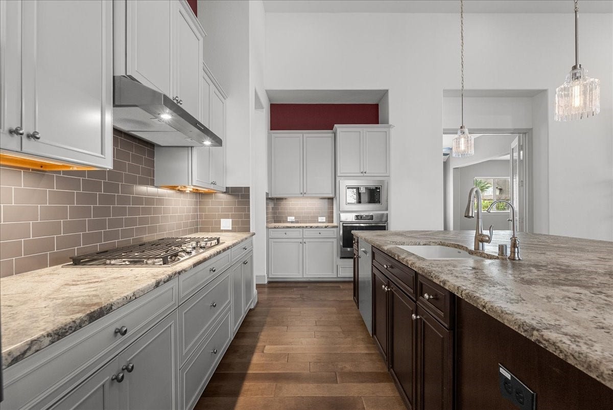 The gourmet kitchen impresses with an oversized granite island, stainless steel appliances, under cabinet lighting, walk-in pantry, and abundant cabinetry.