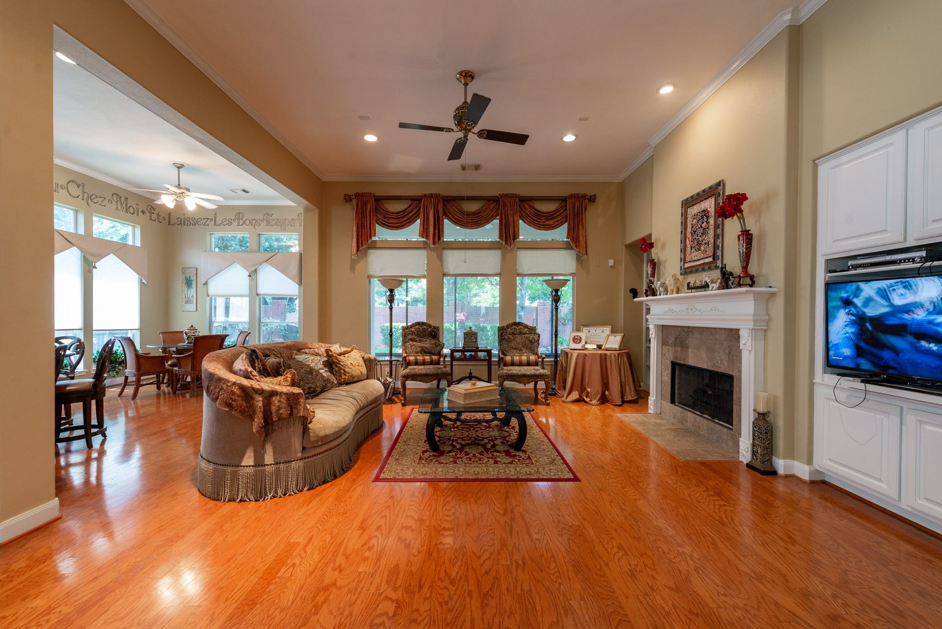 24922 Cinco Manor Lane, Katy, TX 77494 Expansive living room with hardwood flooring, high ceilings, fireplace, built-ins and a wall of windows overlooking the backyard.