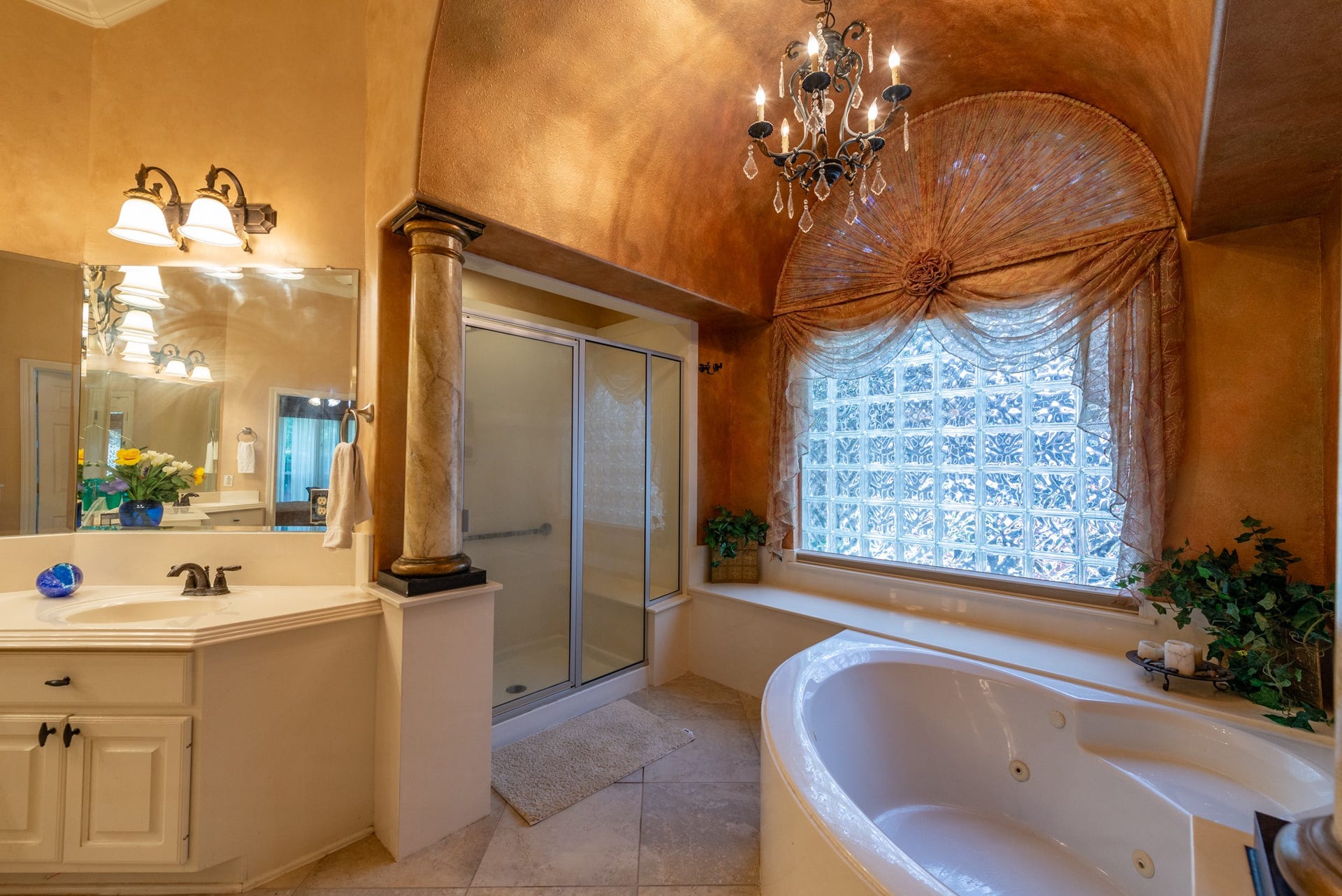 24922 Cinco Manor Lane, Katy, TX 77494 A jetted tub sits beneath a dramatic arched ceiling and glass-block window, with a separate walk-in shower nearby.