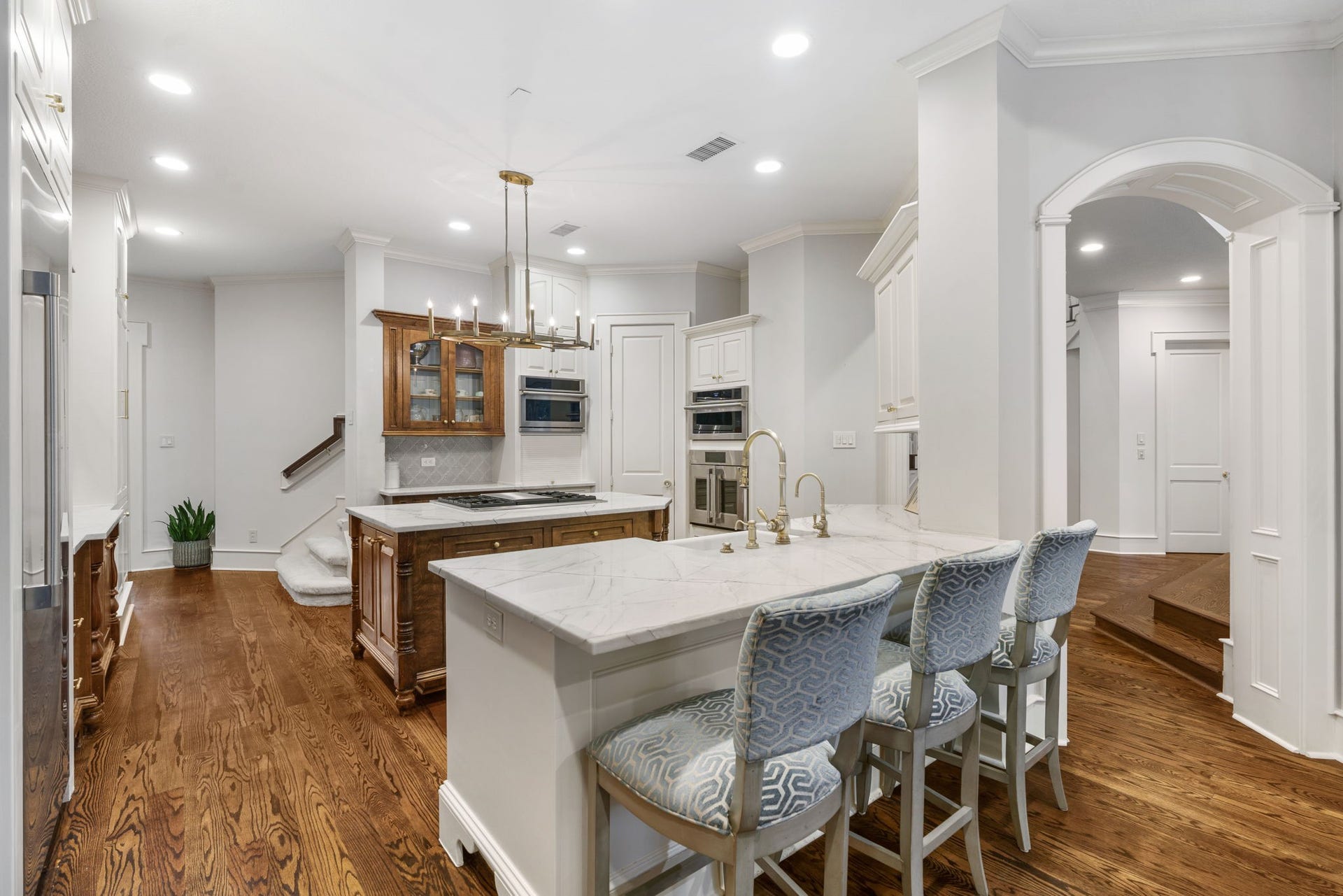 186 Sentinel Point Court, The Woodlands, TX 77382 The kitchen welcomes with a beautiful blend of crisp white cabinetry and warm wood flooring.