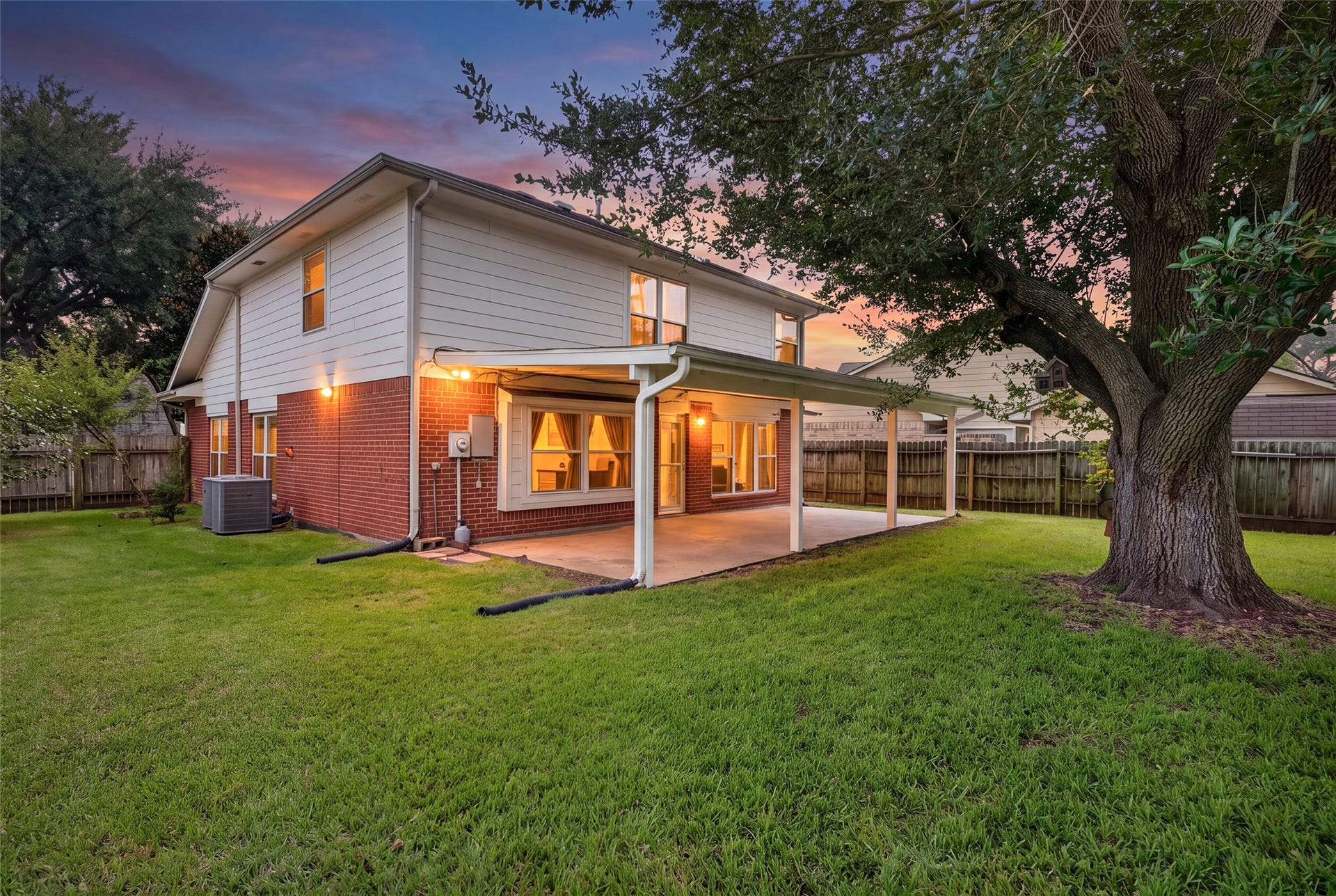 3507 Santa Rosa Lane, Sugar Land, TX 77478 As twilight sets, the peaceful backyard comes to life with glowing indoor lights visible through the expansive windows and glass doors.