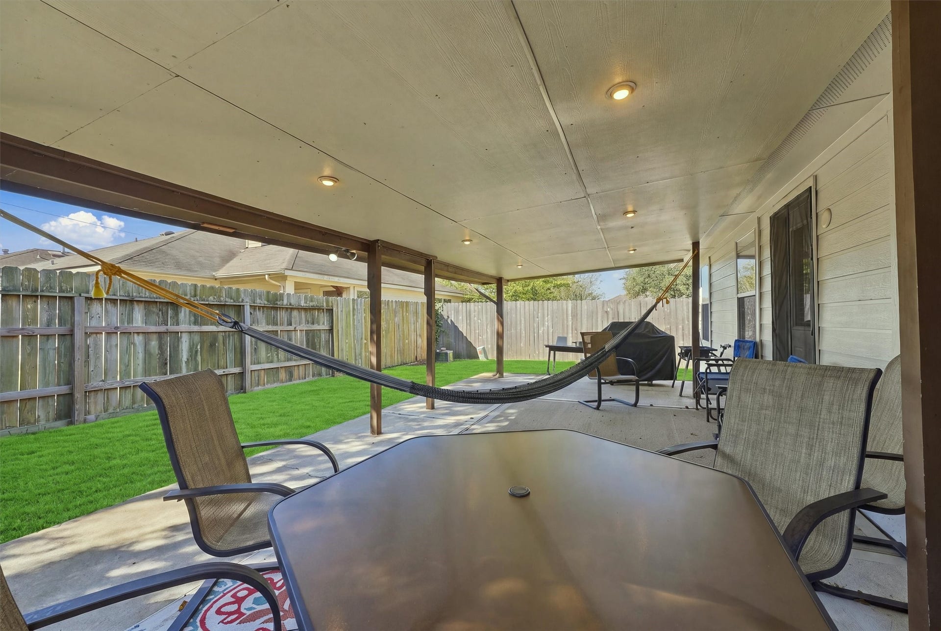 18931 Bonners Park Circle, Katy, TX 77449 Spacious covered patio featuring comfortable seating and a hammock, perfect for relaxing and entertaining in a private fenced backyard.