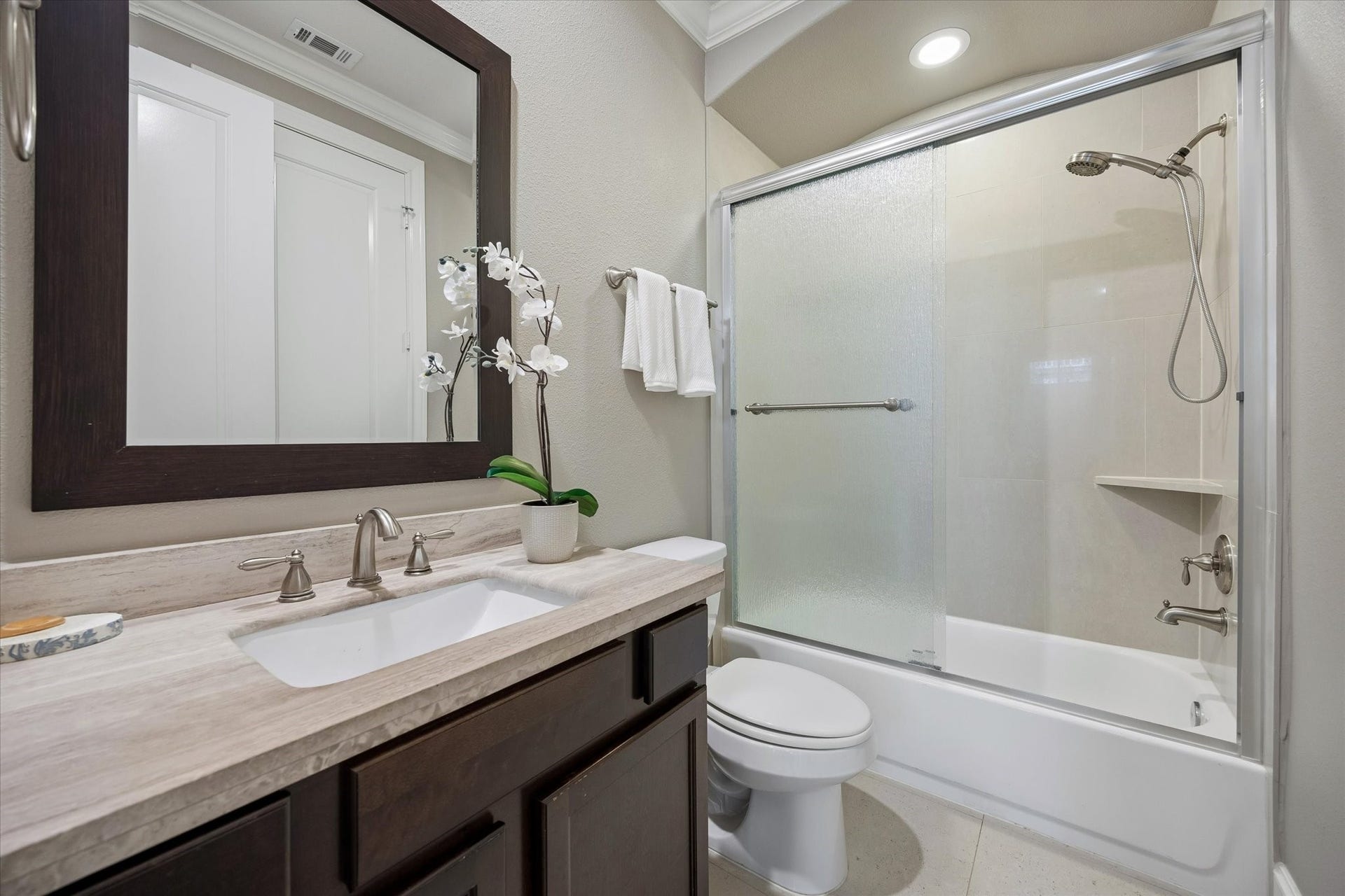 8805 Kolbe Bend Lane, Houston, TX 77080 Adjoining full bath featuring a stone-topped vanity, framed mirror, and tub/shower combination with sliding glass enclosure.