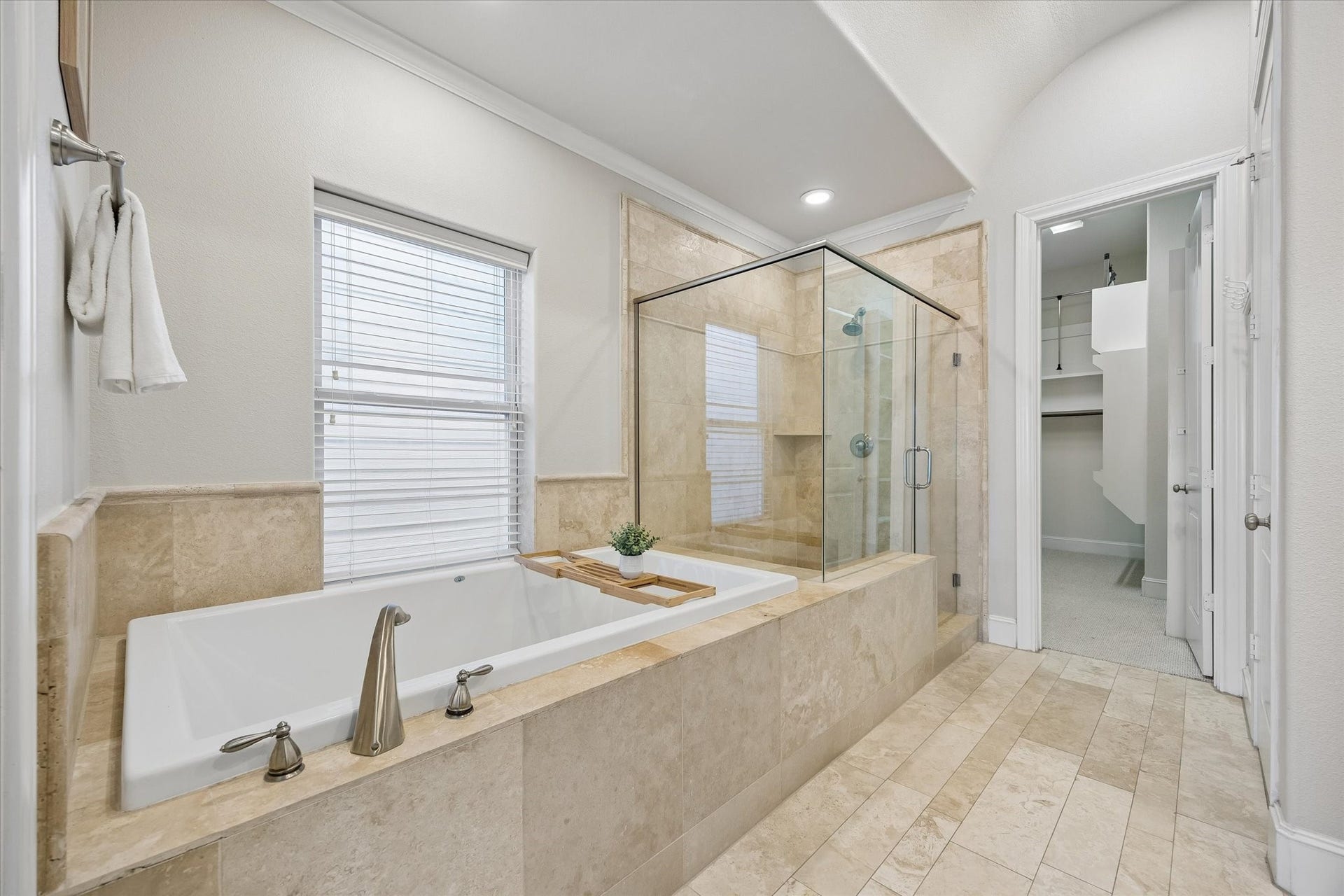 8805 Kolbe Bend Lane, Houston, TX 77080 Primary bath includes a large soaking tub, separate glass-enclosed walk-in shower, natural stone finishes, and access to the walk-in closet.