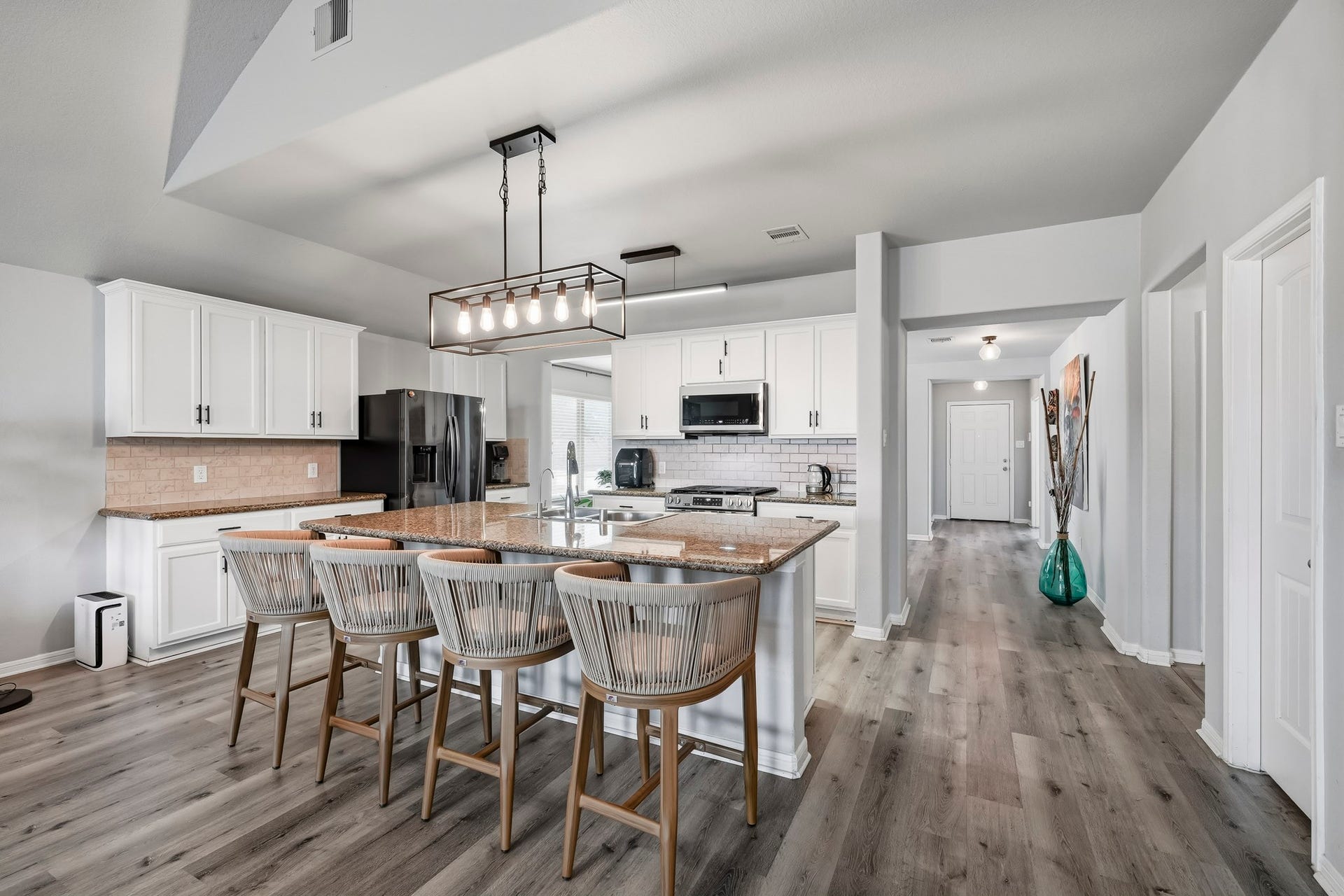 17822 Royal Breccia Lane, Richmond, TX 77407 The spacious kitchen features white cabinetry, granite countertops, a large center island with bar seating, and an open design that connects beautifully with the main living areas.