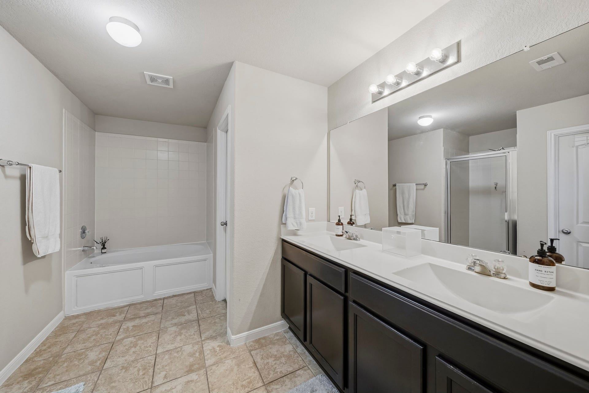 17822 Royal Breccia Lane, Richmond, TX 77407 The spacious primary bathroom with walk-in closet, features dual vanities, a soaking tub, a separate glass-enclosed shower, and generous counter space for a comfortable daily routine.