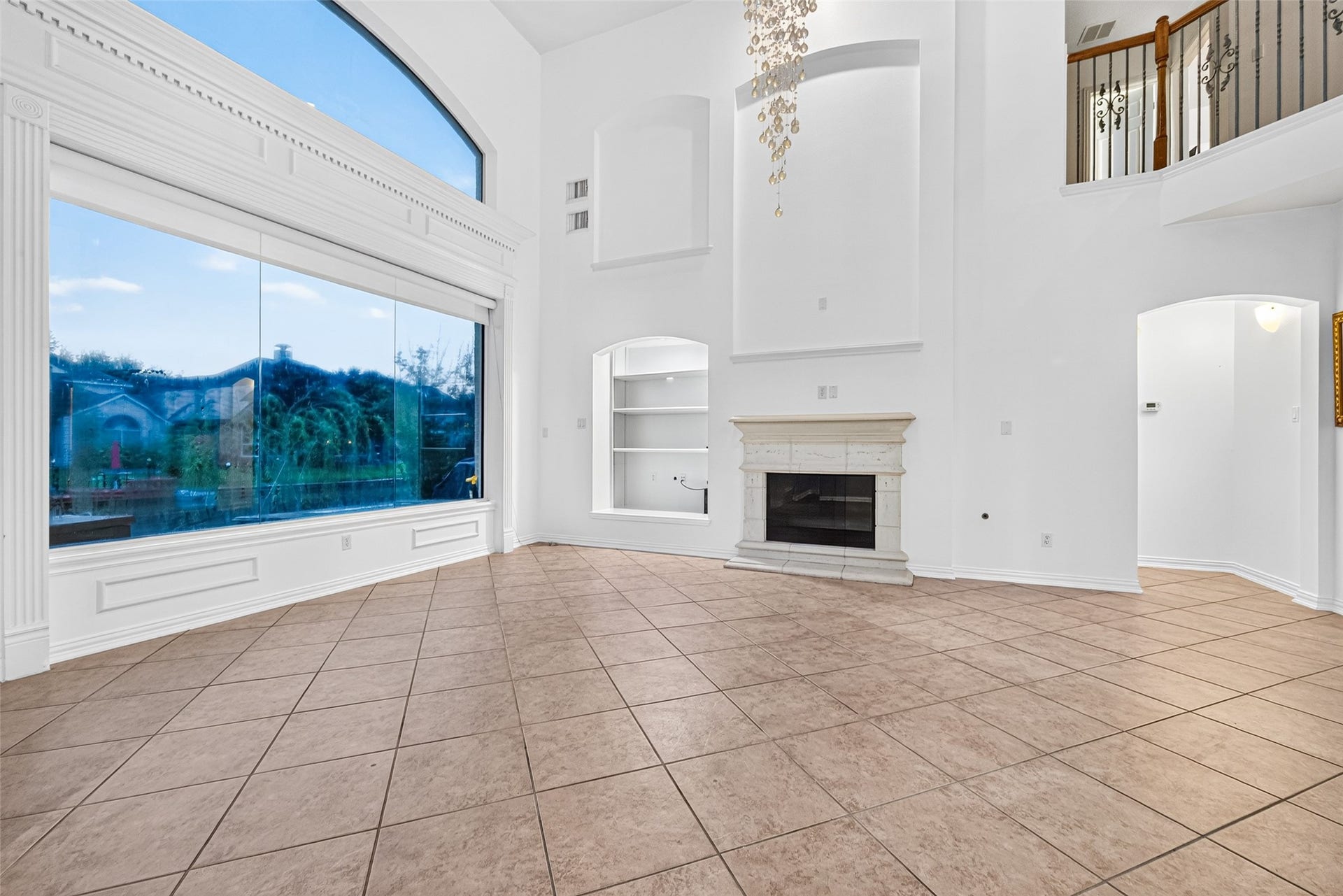 14242 Ashmore Reef Court, Sugar Land, TX 77498 Elegant family room featuring soaring ceilings and a dramatic wall of windows that fills the space with natural light, while a beautiful fireplace creates a warm and inviting focal point for relaxing and entertaining
