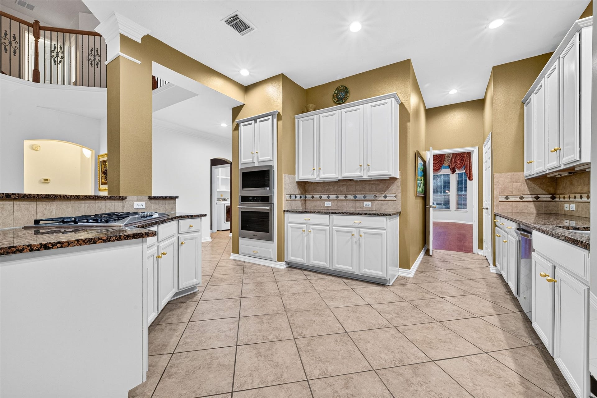 14242 Ashmore Reef Court, Sugar Land, TX 77498 Chefs dream kitchen featuring a sleek gas cooktop, premium built-in stainless steel appliances, and luxurious granite countertops, creating a sophisticated and highly functional space for cooking and entertaining.