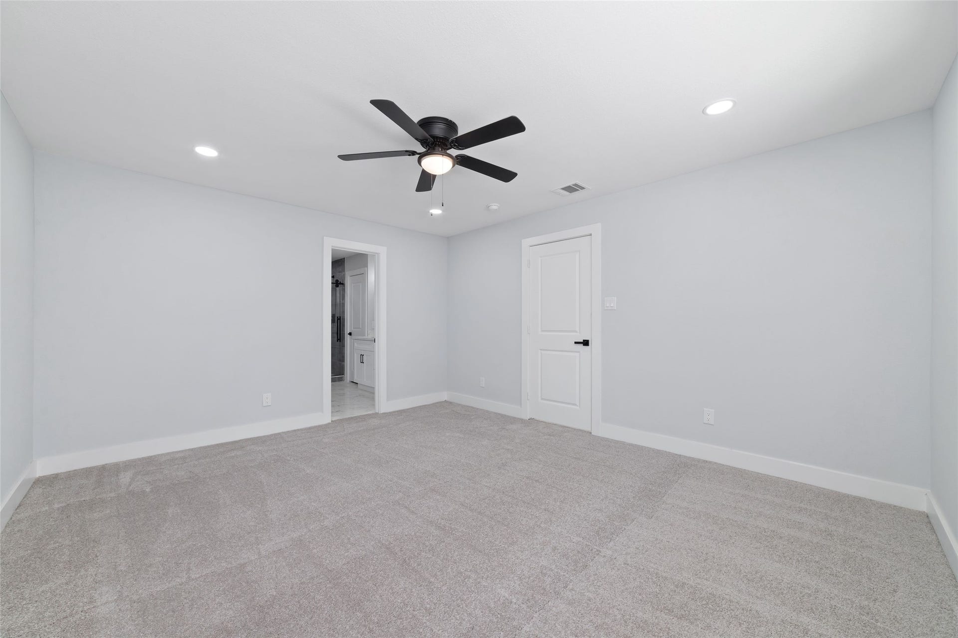 The primary bedroom features neutral tones, carpet flooring, recessed lighting, and a ceiling fan, with an adjoining bathroom.