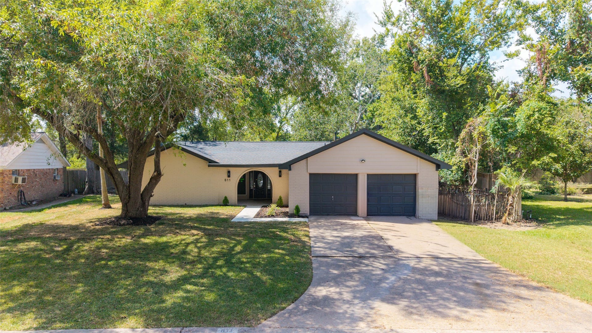 Front exterior showcasing an attached two-car garage, concrete driveway, and landscaped beds near the entry.