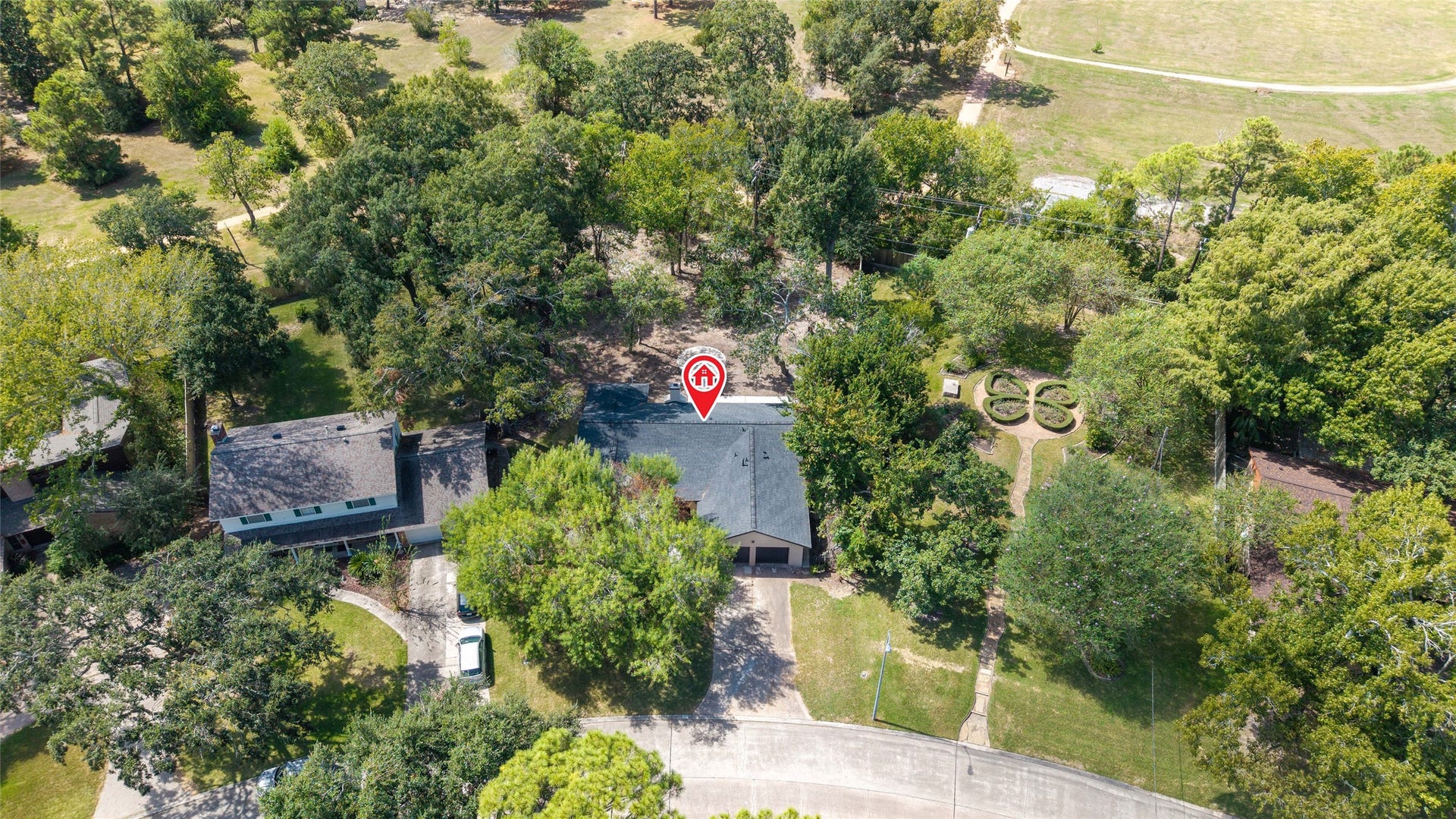 Overhead view showcasing the homes placement on its tree-filled lot, with the front driveway, backyard, and surrounding landscape visible.
