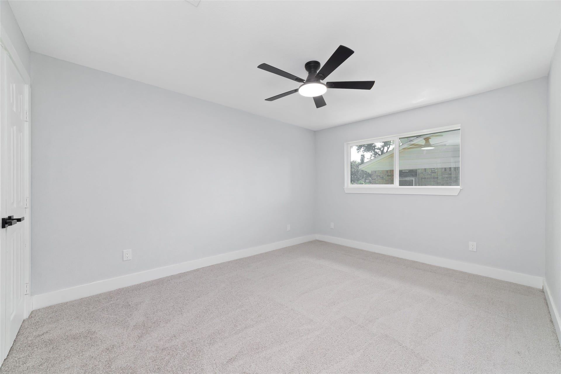 This bedroom features carpet flooring, neutral walls, a ceiling fan, and a double-door closet. A window brings natural light into the space.