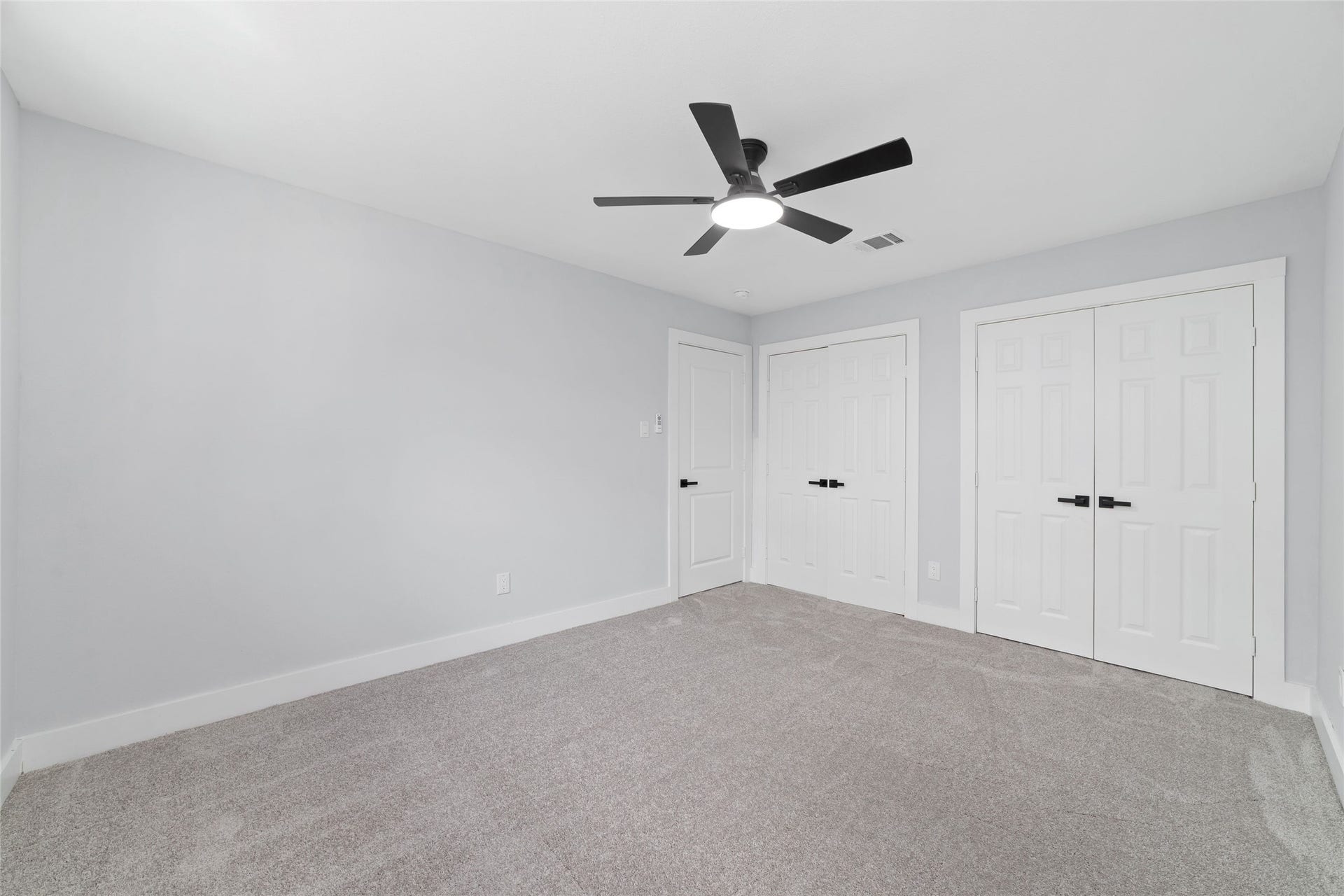 This bedroom features carpet flooring, neutral walls, a ceiling fan, and a double-door closet. A window brings natural light into the space.
