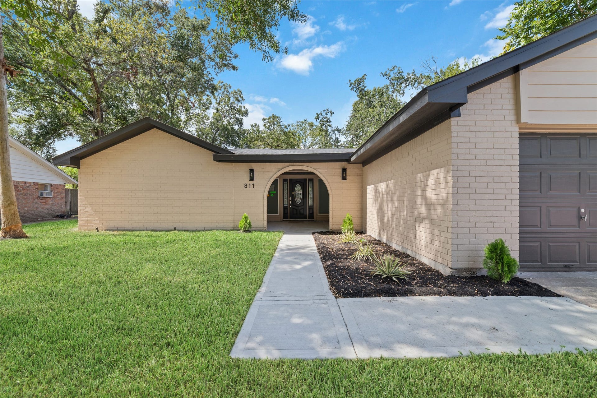A distinctive arched entrance and decorative glass front door create a welcoming first impression.