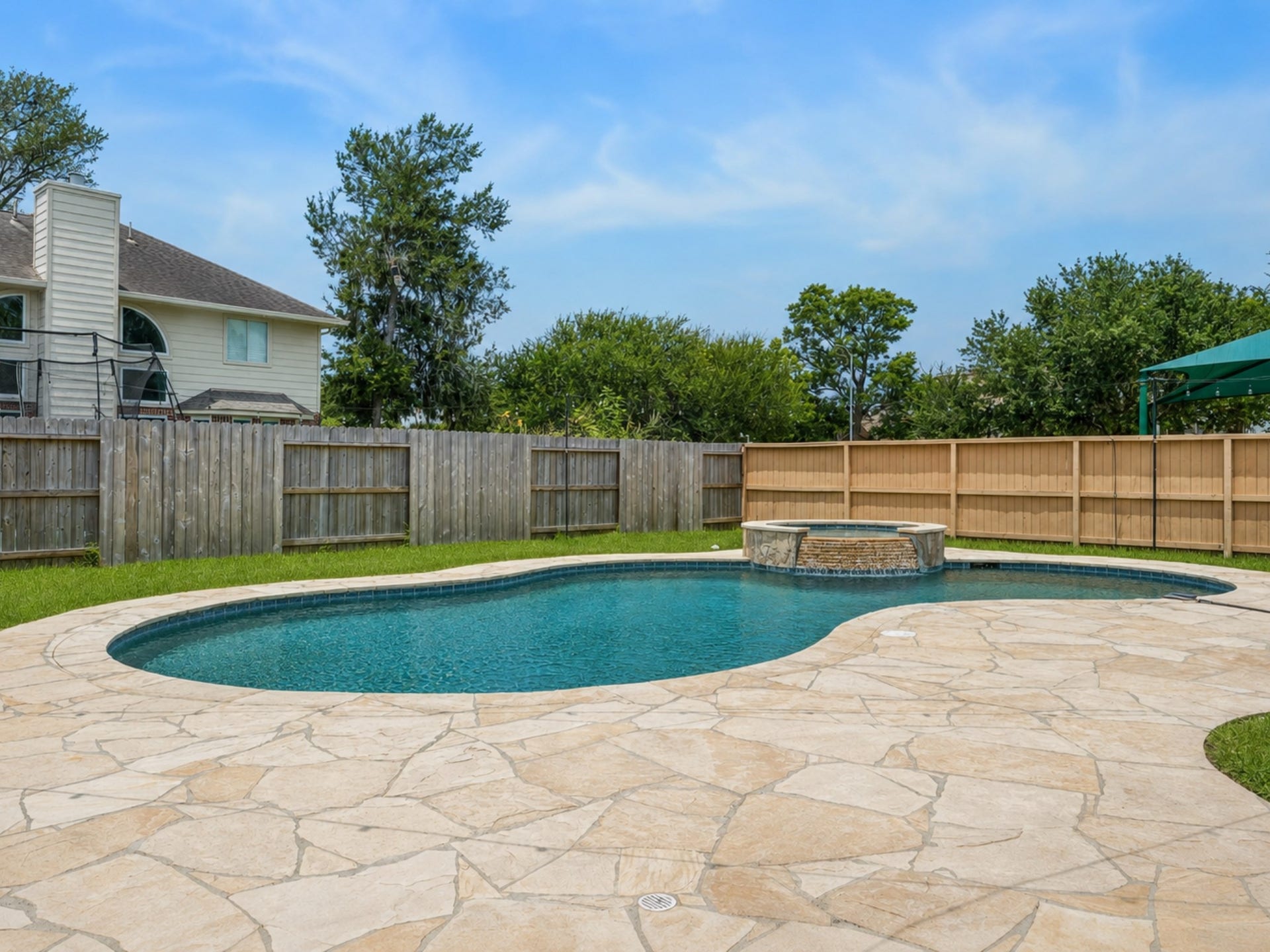 The backyard features an inviting pool, expansive patio, and covered outdoor living space.