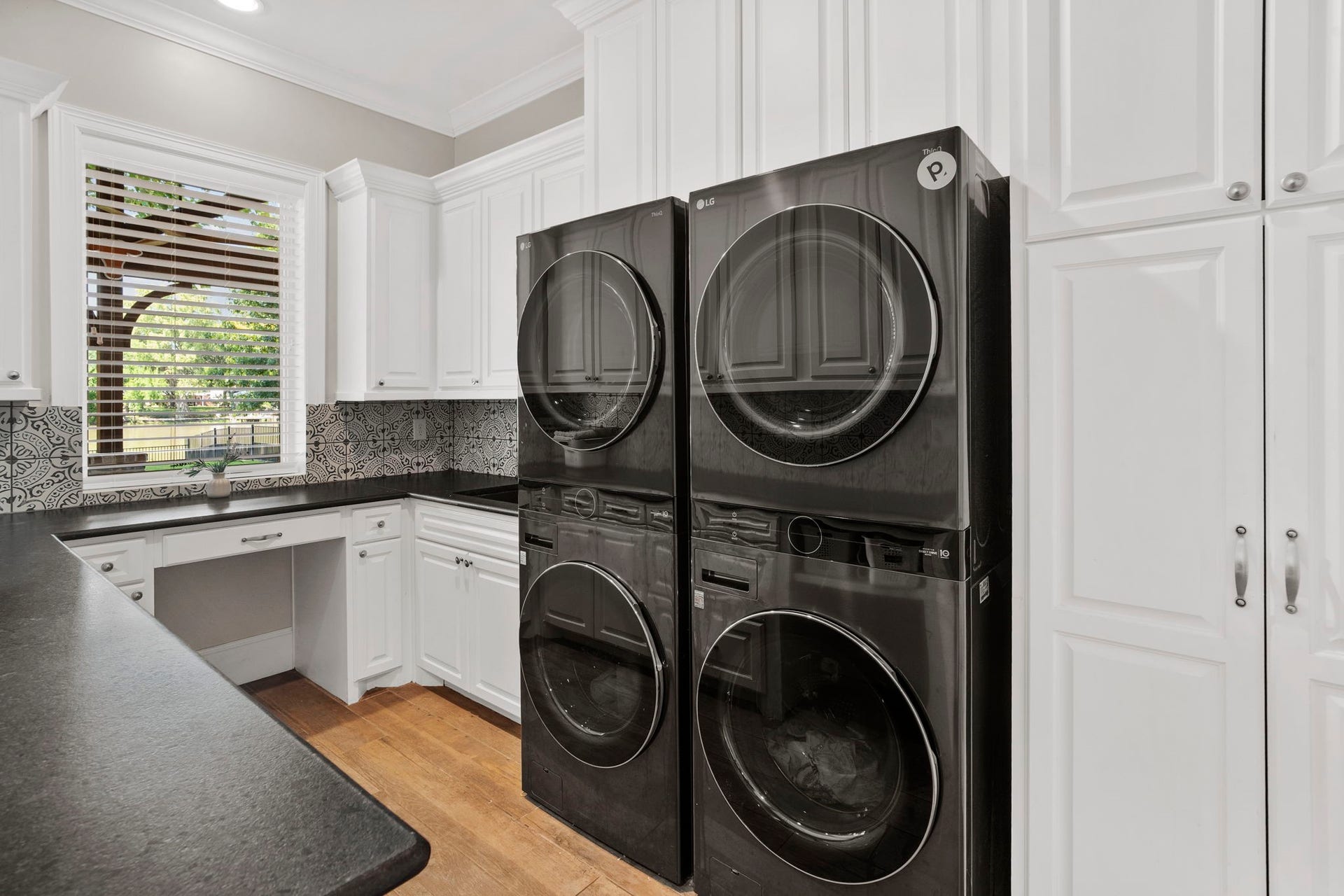 706 Oyster Creek Drive, Sugar Land, TX 77478 Dream laundry room offers abundant counter space and storage, a built-in desk area, and room for two washers and two dryers. A large window overlooks the water, bringing in natural light and creating an inviting space for everyday tasks.