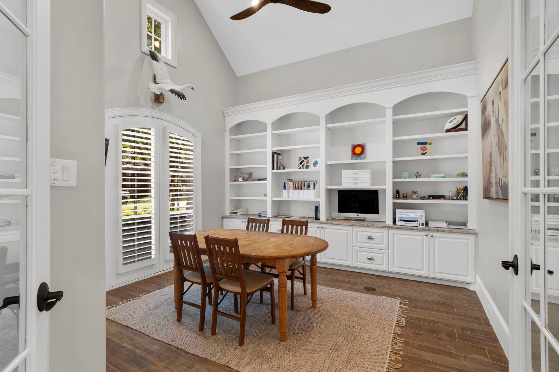 706 Oyster Creek Drive, Sugar Land, TX 77478 French doors open to a home office featuring a vaulted ceiling and a wall of custom built-in shelving and storage cabinets.
