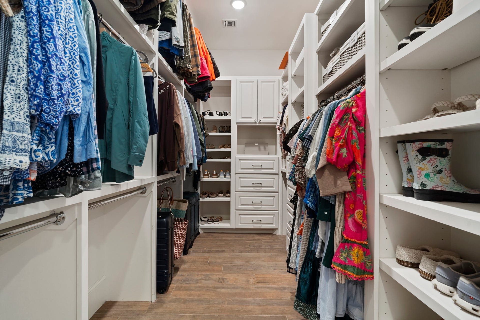 706 Oyster Creek Drive, Sugar Land, TX 77478 Drawers, shelving, and multiple tiers of hanging racks, provide exceptional storage in this spacious 20' x 16' owners walk-in closet featuring custom built-in cabinetry with abundant