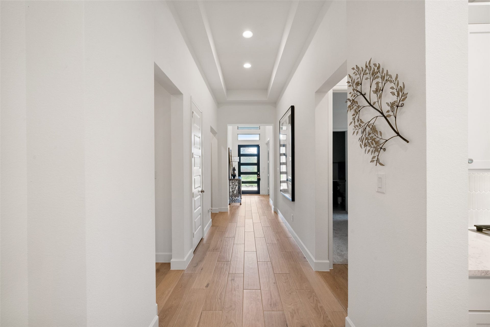 118 Sierra Stream Court, Conroe, TX 77304 Beautiful extended hallway features a distinctive tray ceiling, recessed lighting, and warm wood-look flooring. Thoughtful architectural details create an elegant transition between the home's living spaces.