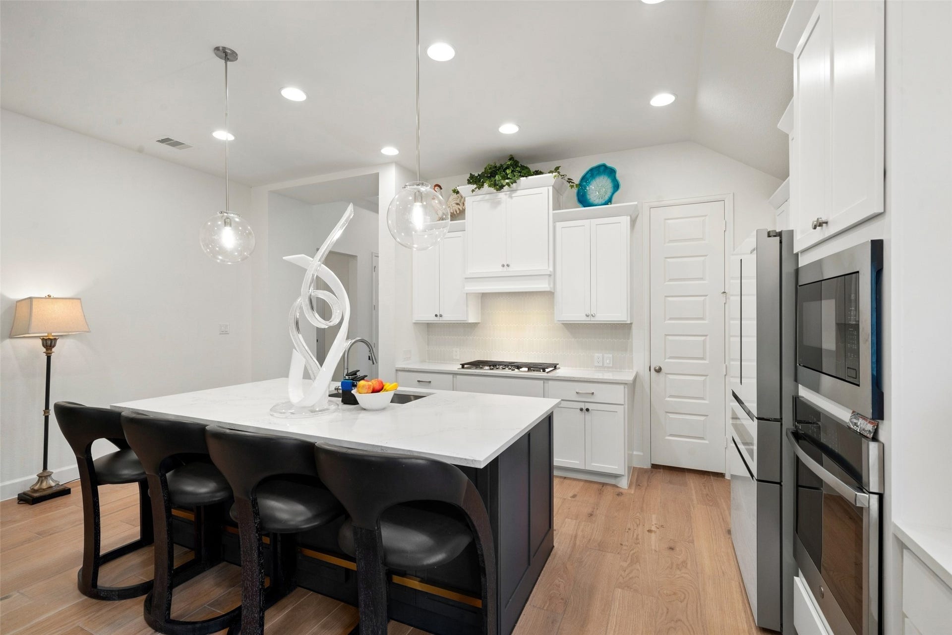 118 Sierra Stream Court, Conroe, TX 77304 Beautifully designed kitchen showcases a generous center island with seating, crisp white cabinetry, sleek countertops, and stainless steel appliances. Elegant glass pendant lighting adds a refined finishing touch.