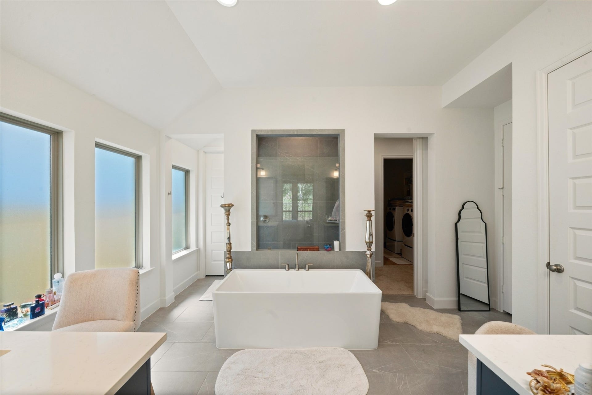 118 Sierra Stream Court, Conroe, TX 77304 Beautifully appointed primary bath showcases a freestanding soaking tub positioned before an expansive glass-enclosed shower with contemporary tilework. Multiple windows provide abundant natural light while maintaining privacy.