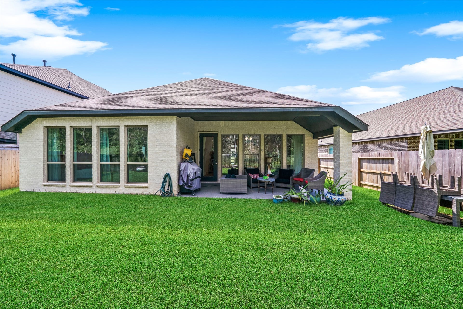 118 Sierra Stream Court, Conroe, TX 77304 Attractive rear elevation showcases expansive windows, beautiful light-colored brickwork, and a generous covered patio designed for outdoor enjoyment. The spacious backyard offers plenty of room for entertaining, recreation, or simply relaxing.