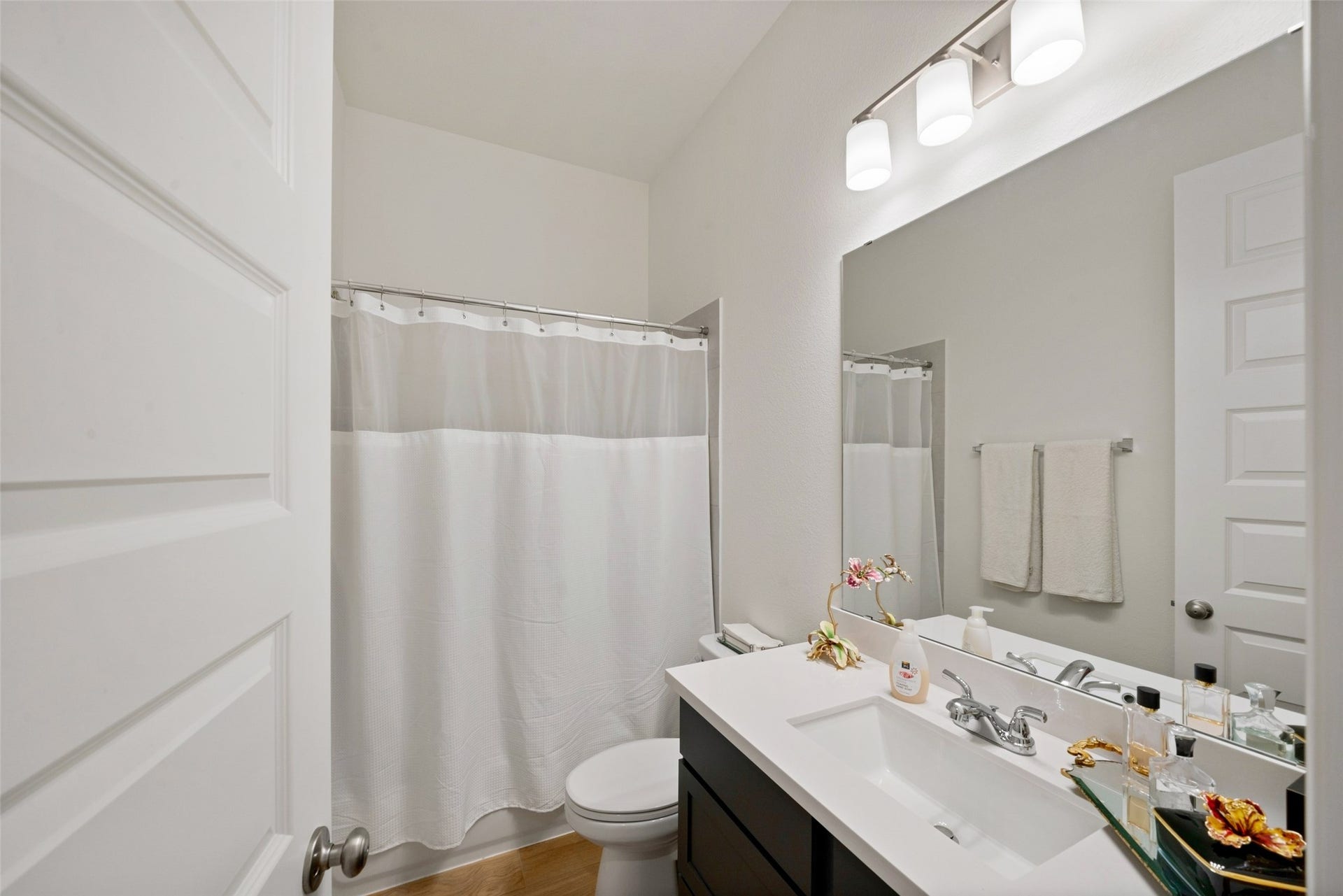 118 Sierra Stream Court, Conroe, TX 77304 Well-appointed secondary bathroom showcases a sleek dark vanity, white countertop, contemporary lighting, and a tub-shower combination. Clean lines and neutral finishes provide a fresh, inviting atmosphere.