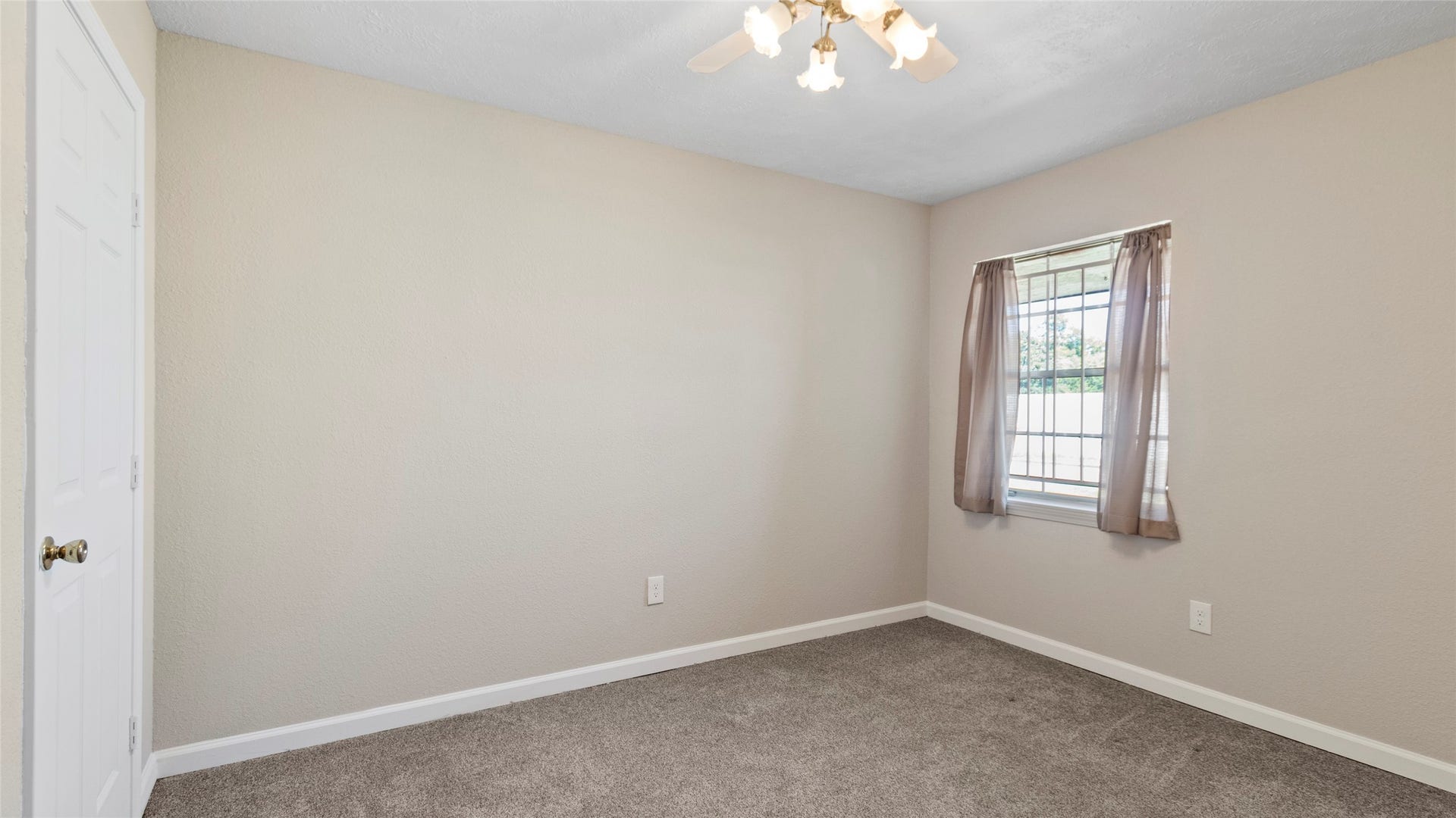 Bedroom with neutral colors, natural light, and a ceiling fan.