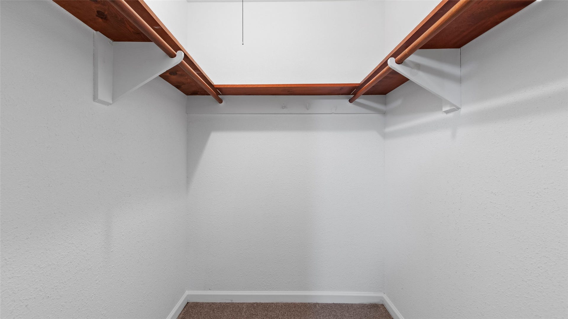 Walk-in closet with shelving and hanging space on both sides.
