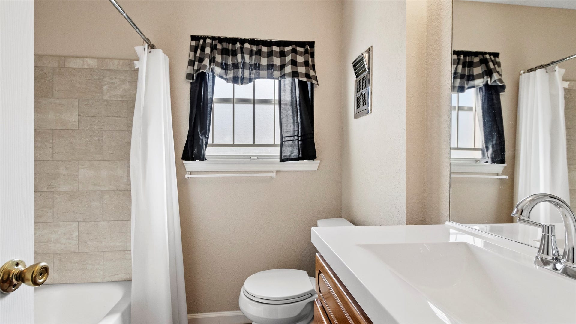 Updated bathroom with a white vanity top and tiled tub/shower combination.