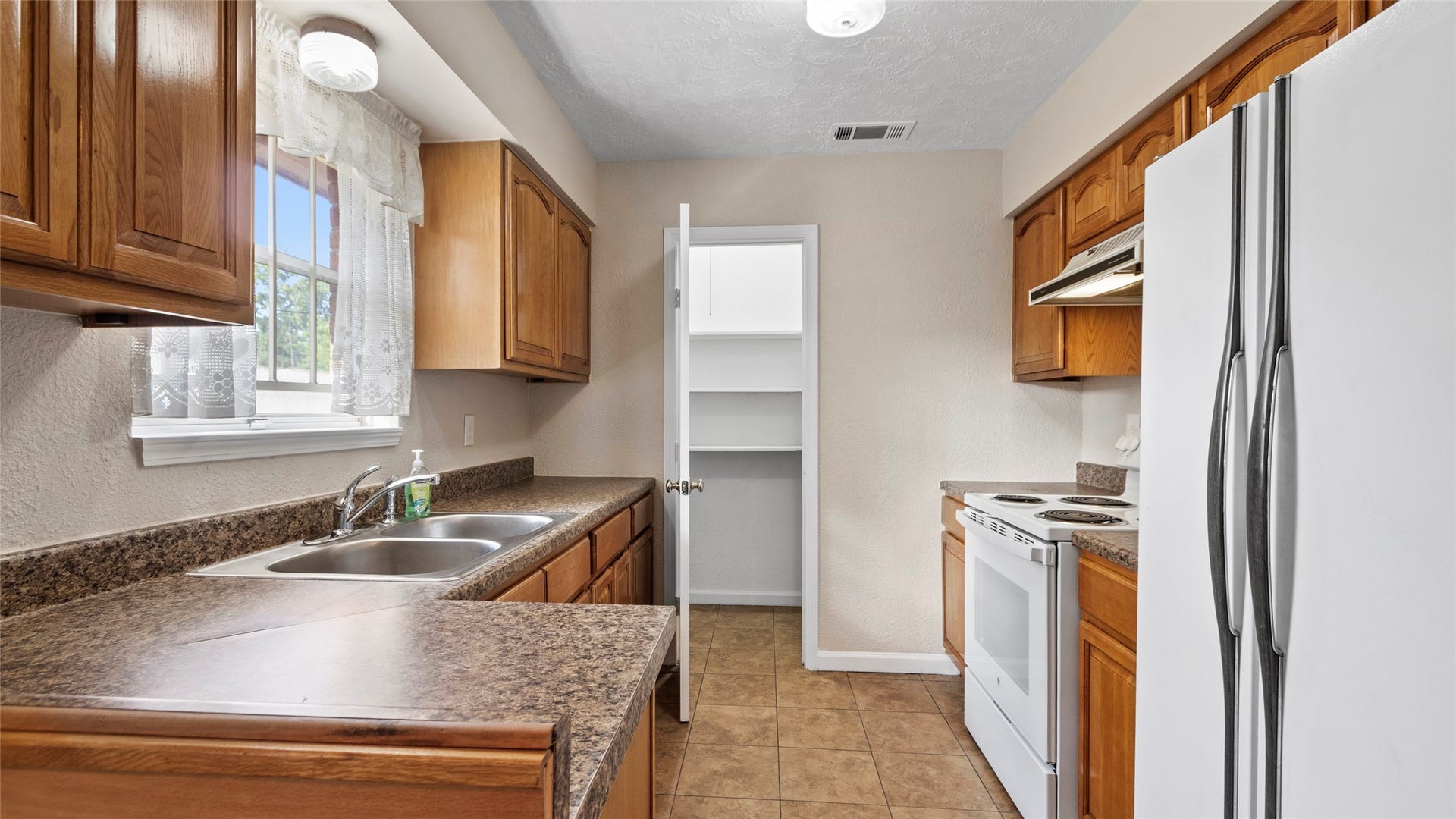 Kitchen with ample cabinet storage, a double-basin sink, and walk in pantry.
